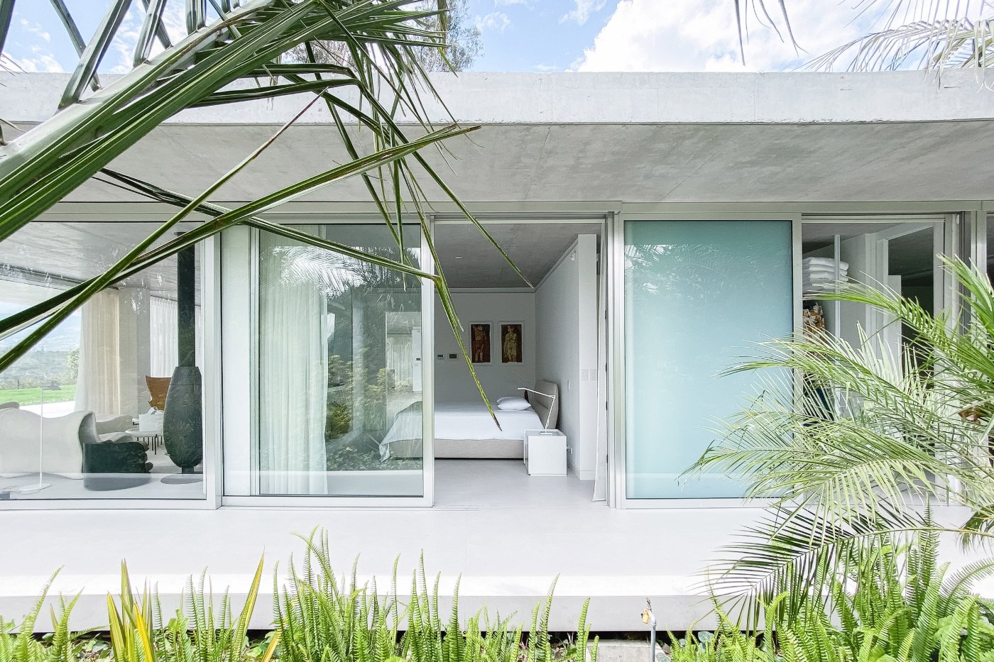 Magnolia House by Estudio Felipe Escudero — The bedroom wing extends into the garden through expansive sliding glass doors that dissolve the boundary between interior and landscape.