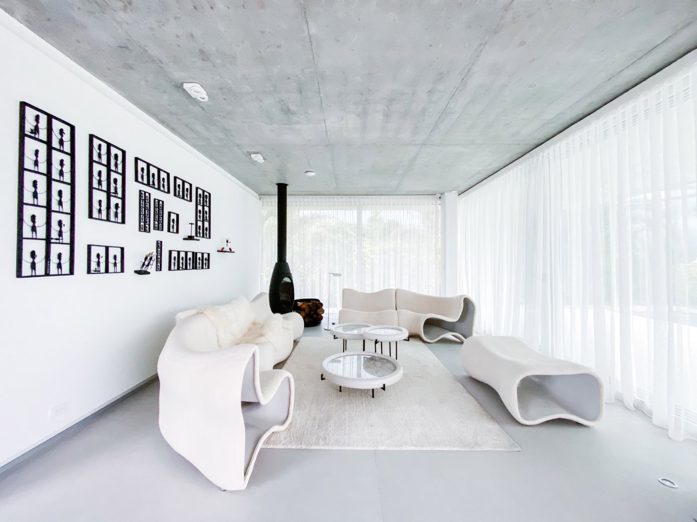 Magnolia House by Estudio Felipe Escudero — The interior living space centers on sculptural white furniture with organic curved forms that echo the building's concrete architecture.