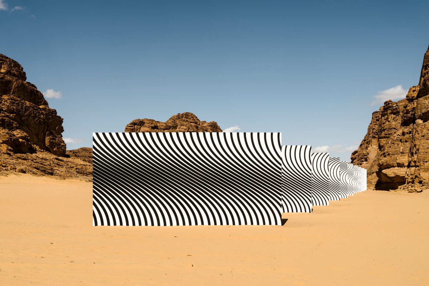 Desert X AlUla 2022 Group Exhibition — A monumental sculptural installation occupies the desert floor between two naturally eroded sandstone cliffs.