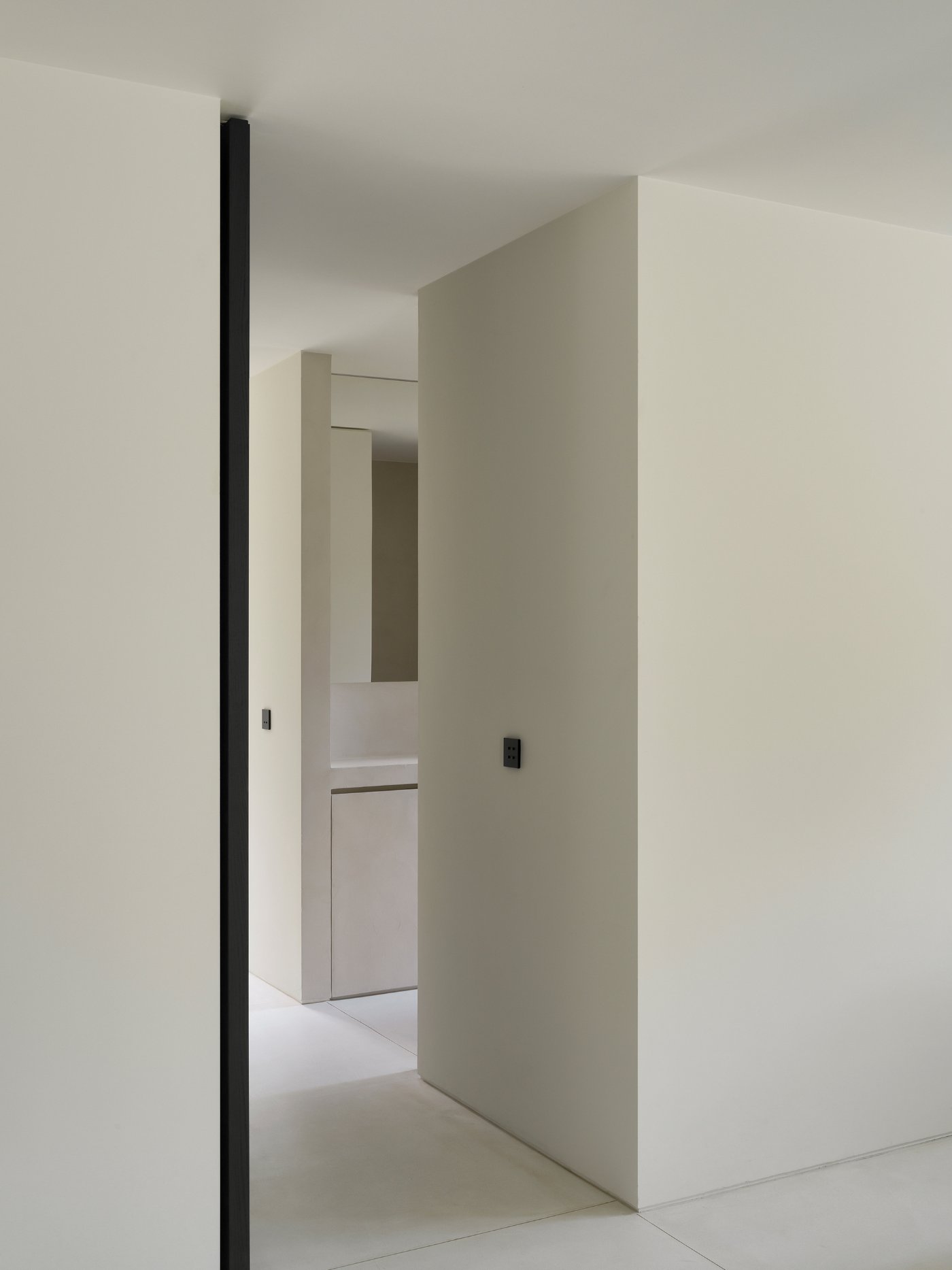 Villa BA by gosseye + verbeke — A passage leading to Villa BA's entrance, framed by board-formed concrete walls in grey and cream tones.