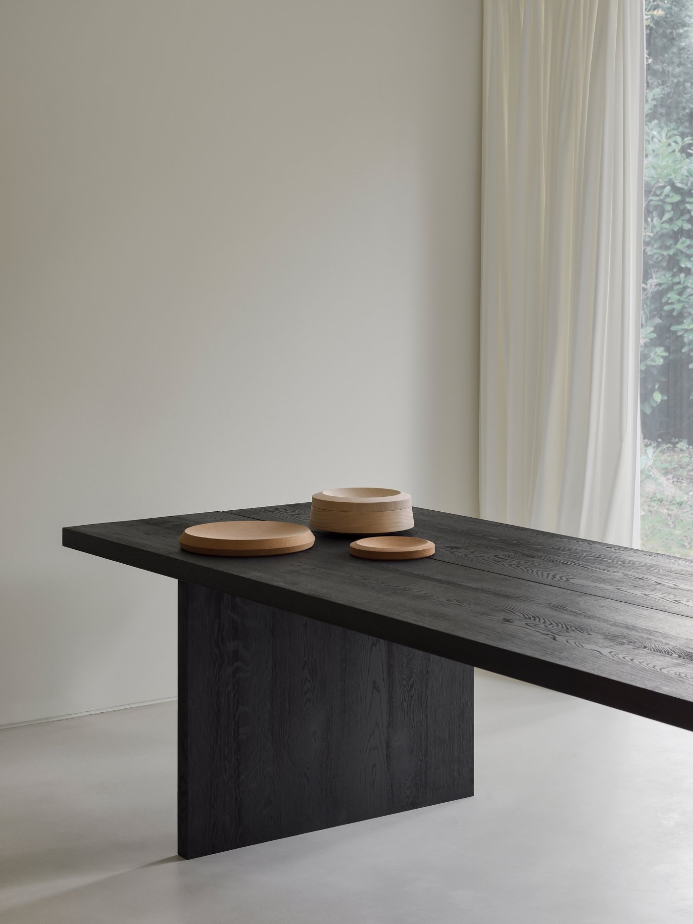 Villa BA by gosseye + verbeke — A black timber table with board-formed wood grain texture dominates the minimalist interior.