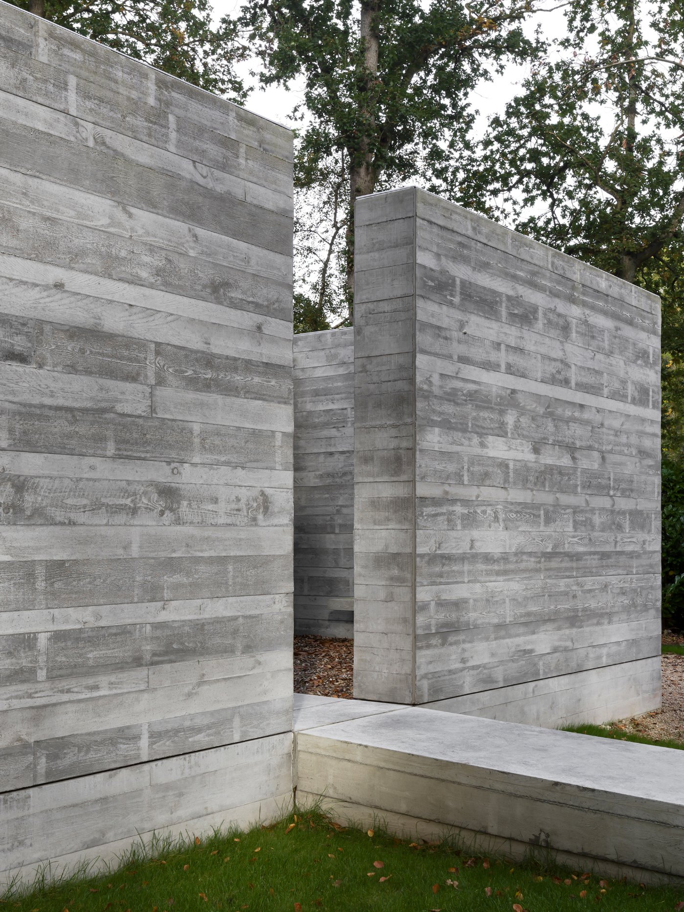 Villa BA by gosseye + verbeke — Villa BA presents a board-formed concrete entrance structure that fragments the facade into two symmetrical planes.