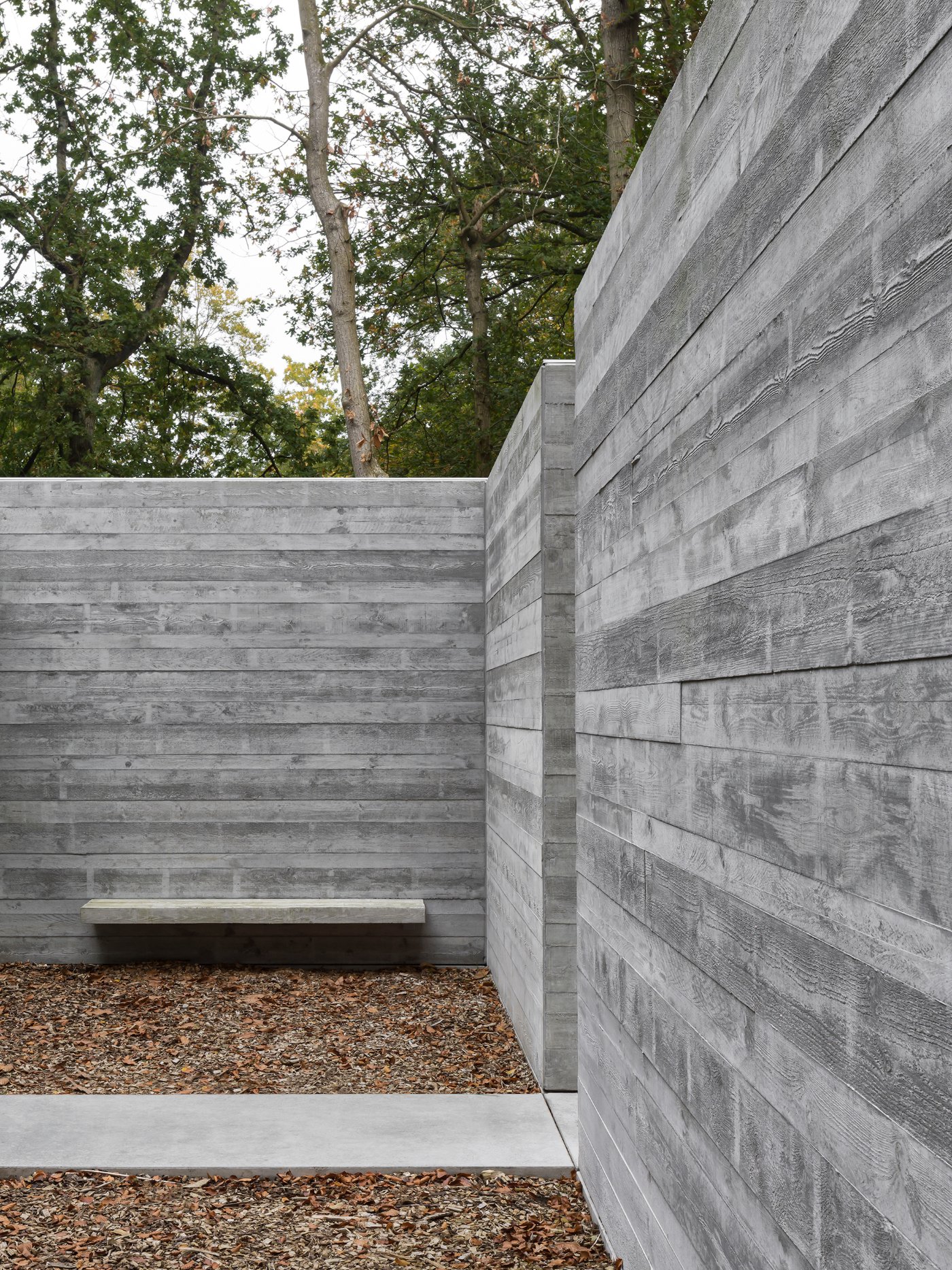 Villa BA by gosseye + verbeke — A concrete courtyard framed by board-formed walls creates a compressed threshold between forest and dwelling.