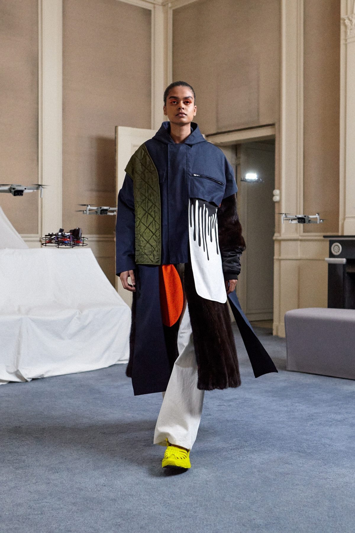 SSAW22 by Duran Lantink — A model presents Duran Lantink's SSAW22 collection in a neutral interior marked by cream-colored flush doors and grey flooring.