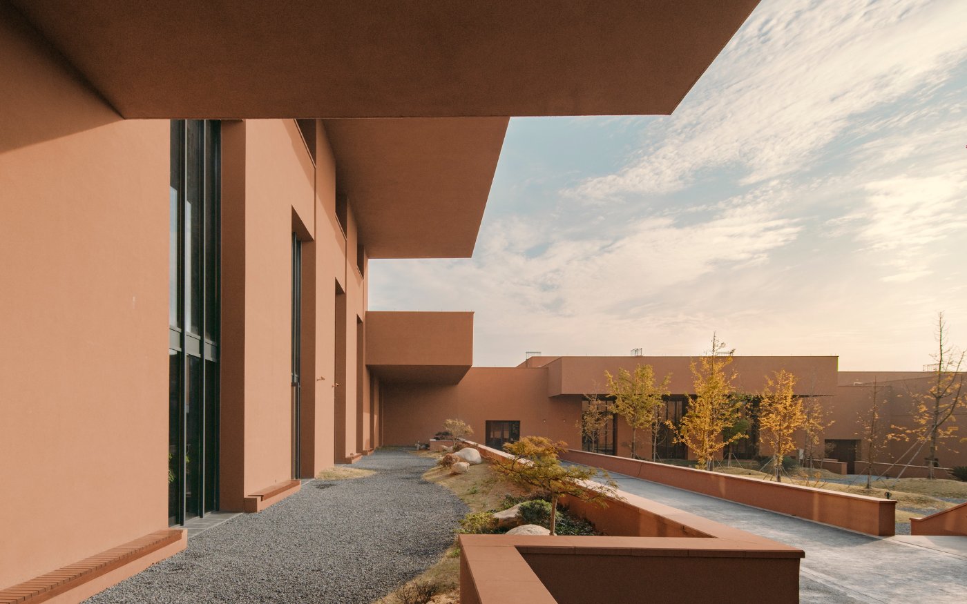 Zhejiang Museum of Natural History by David Chipperfield Architects — Two parallel rendered concrete walls in warm terracotta create a monumental portal framing the landscape beyond.