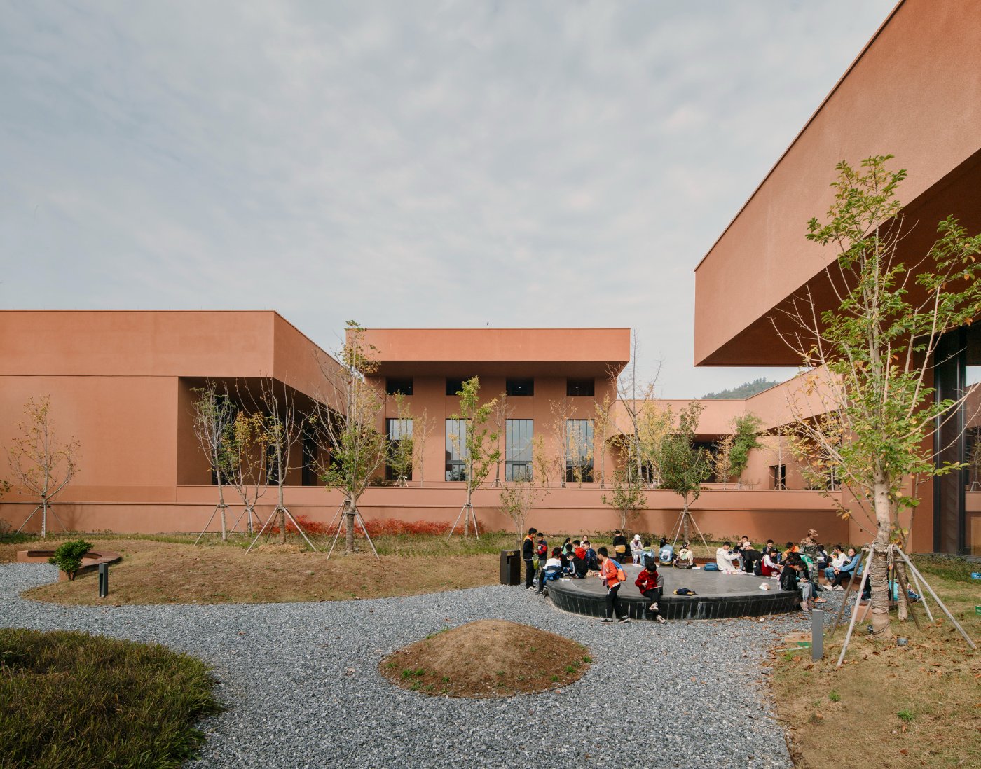 Zhejiang Museum of Natural History by David Chipperfield Architects — A terracotta-rendered courtyard pavilion designed by David Chipperfield Architects frames a landscape view of forested hills beyond.