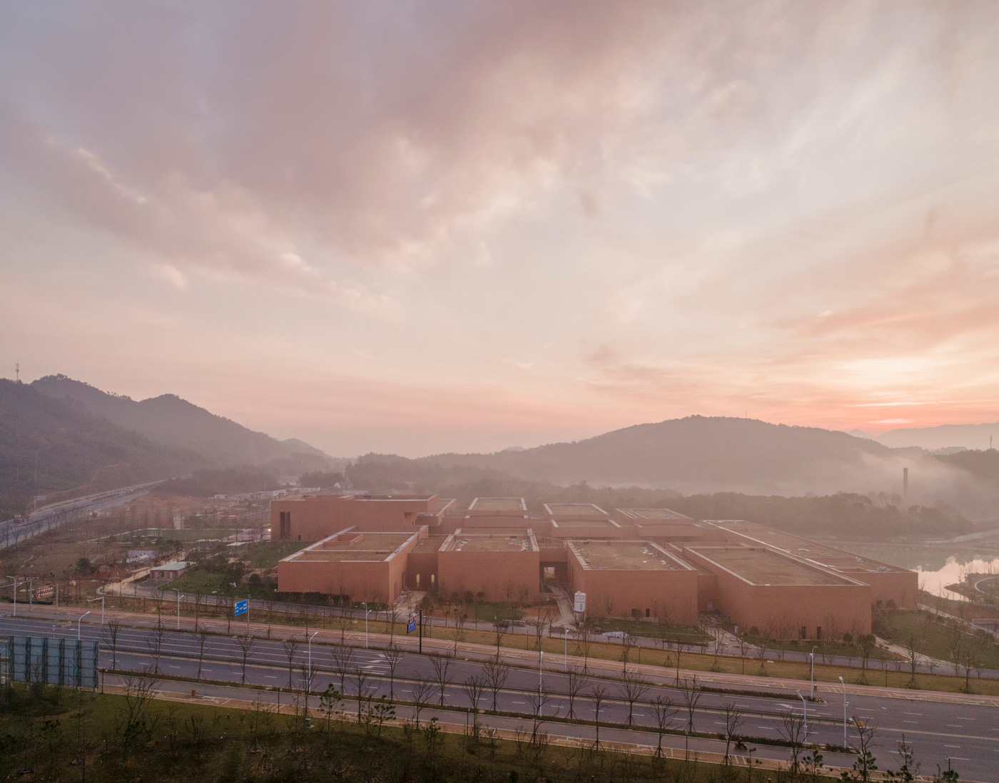 Zhejiang Museum of Natural History by David Chipperfield Architects — David Chipperfield Architects' Zhejiang Museum of Natural History emerges from the misty valley landscape as a monolithic terracotta structure.