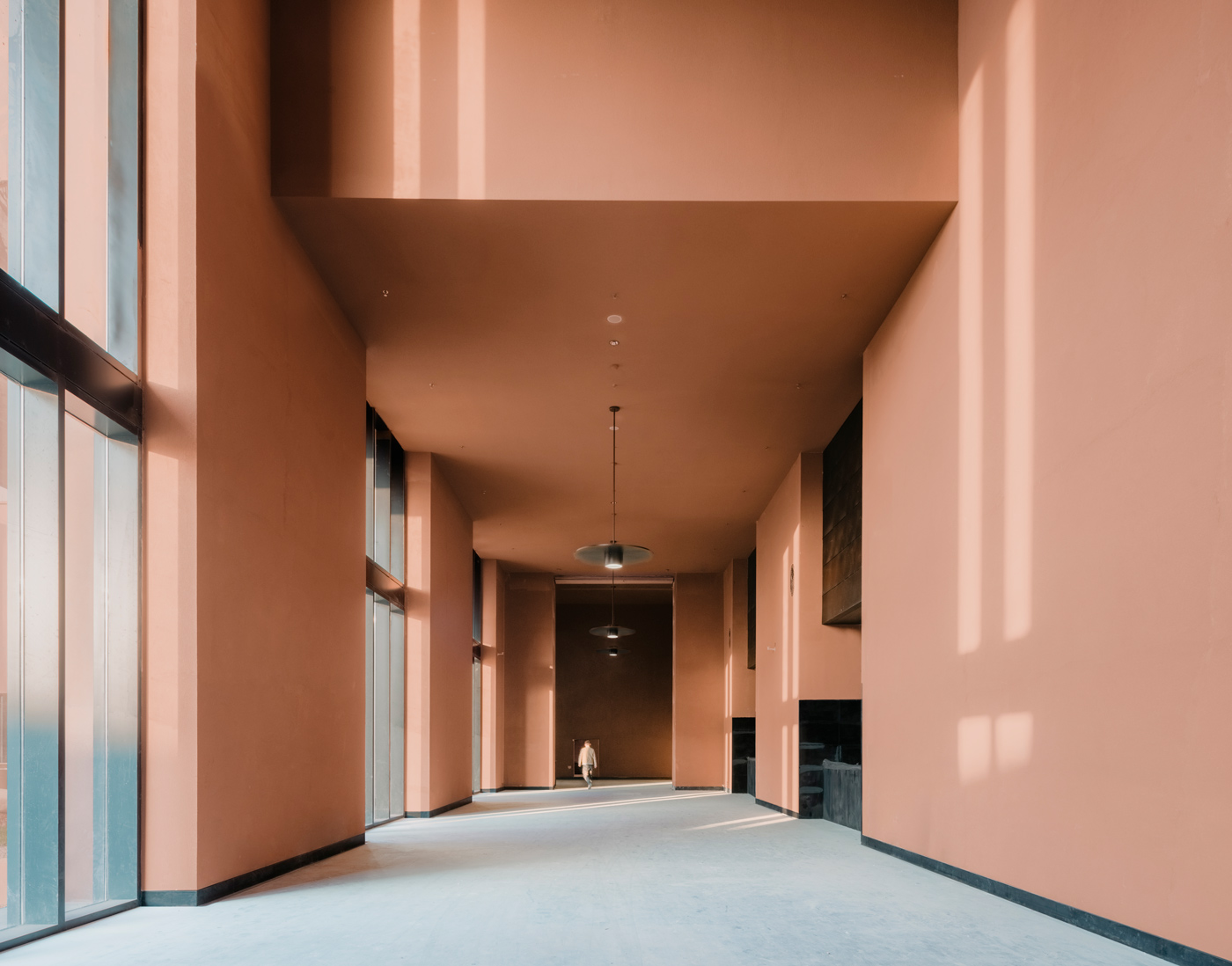 Zhejiang Museum of Natural History by David Chipperfield Architects — A rendered concrete passage in warm terracotta opens toward the landscape beyond, its perfectly symmetrical walls framing a distant forested hillside.