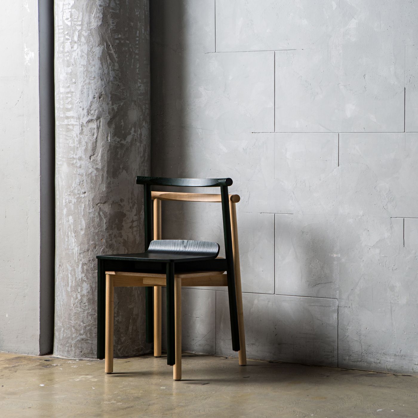 Wox collection by Pavel Vetrov for Artu — The Wox chair by Pavel Vetrov sits isolated against a raw concrete wall and cylindrical column in a minimal studio setting.