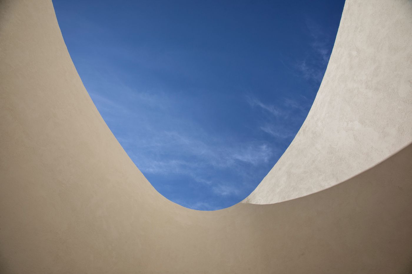 Haight Clothing Store by Entre Terras & Pablo Resende — Overhead framing captures the project's defining spatial choreography: a curved concrete archway frames clear blue sky, its generous opening creating a...