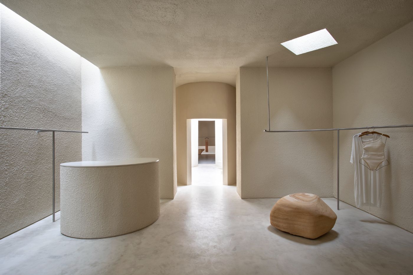 Haight Clothing Store by Entre Terras & Pablo Resende — A clothing boutique interior organized as a spatial sequence around a central wooden sculptural form.
