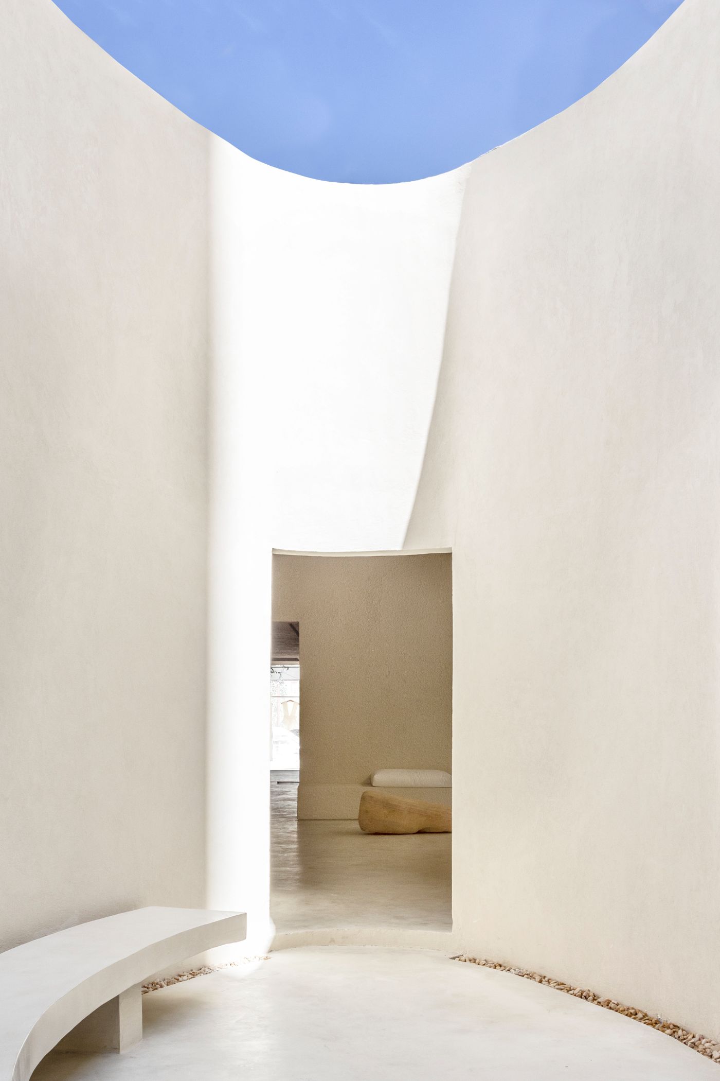 Haight Clothing Store by Entre Terras & Pablo Resende — A sculptural passage frames the transition between rooms through a monolithic archway.