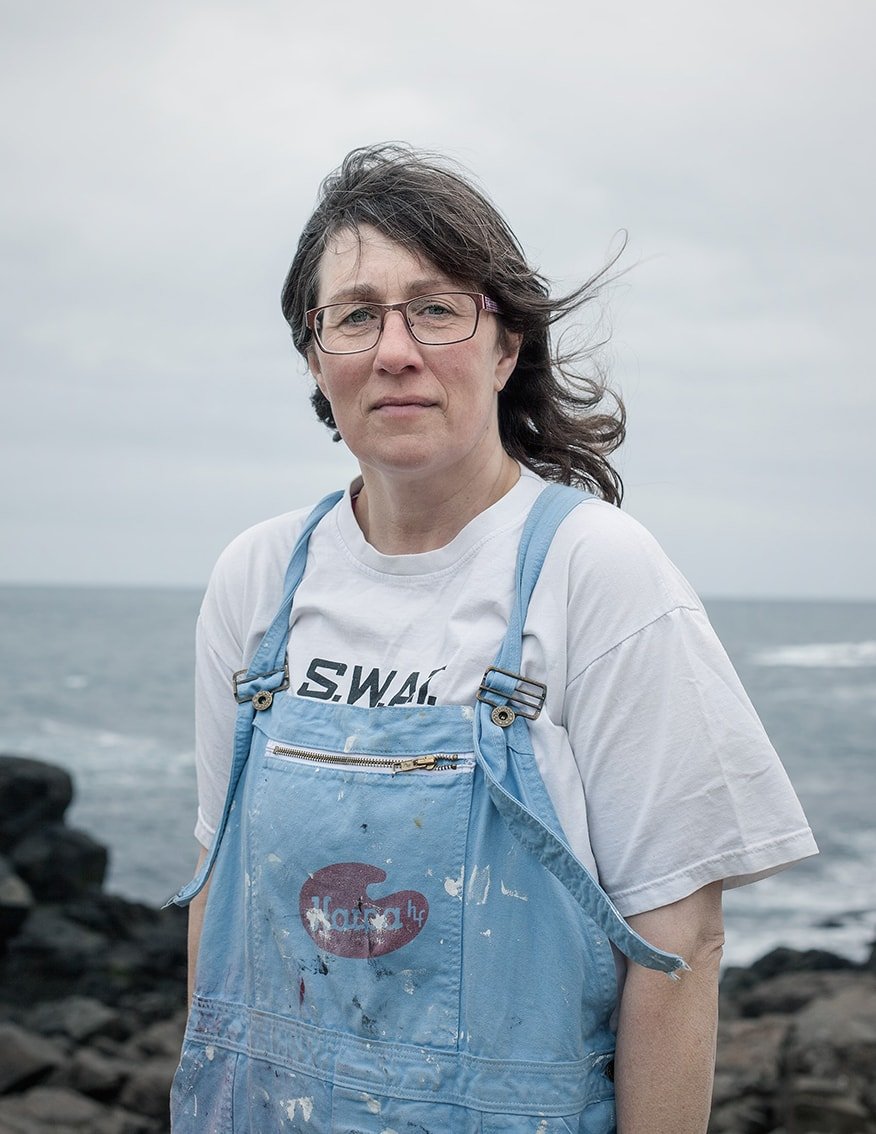 The Weather Report by Marzena Skubatz — Portrait of the weather station operator at Marsibil, Iceland, positioned against the grey Atlantic horizon.