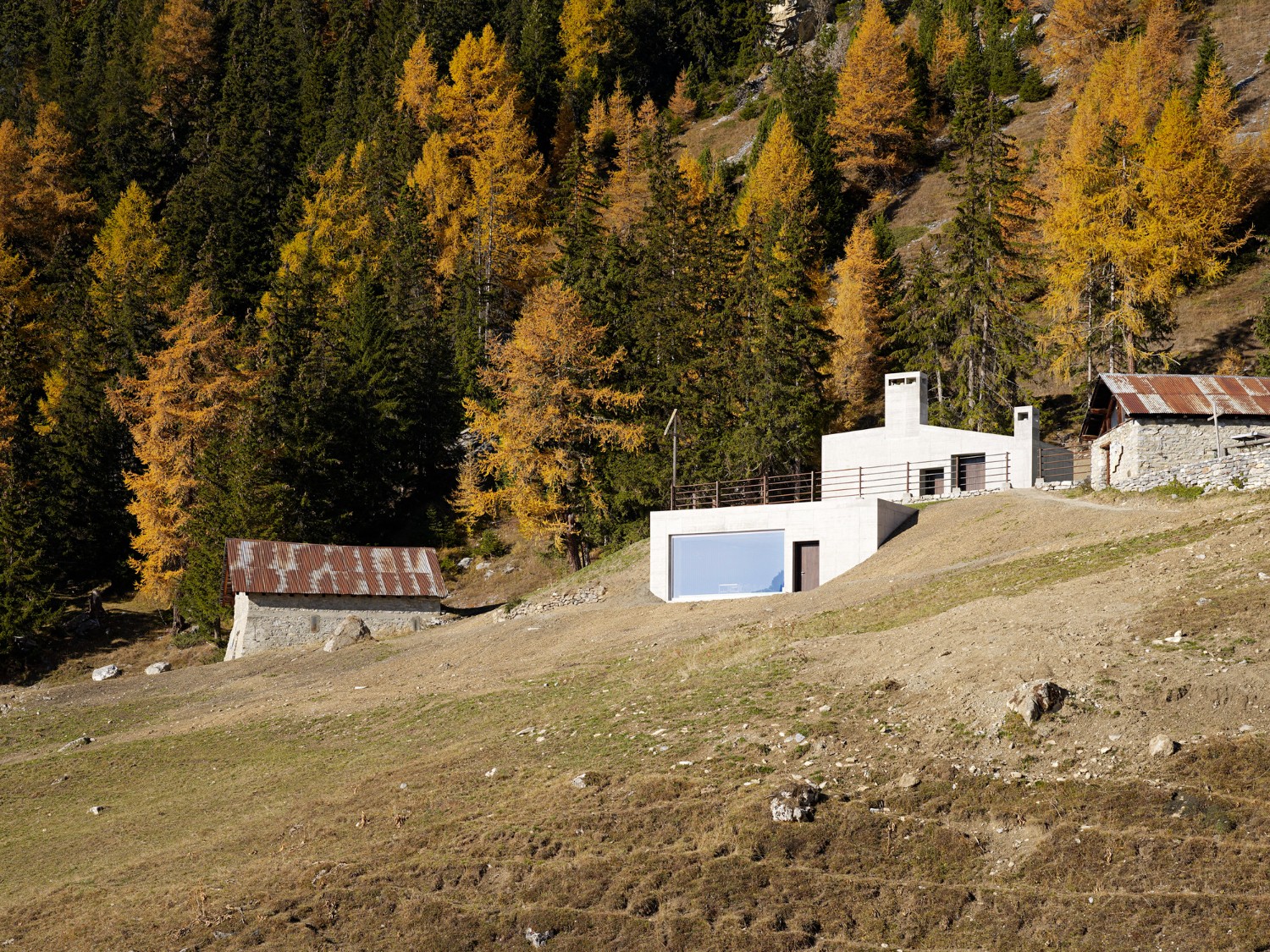 Community Shelter by frundgallina — A modernist concrete shelter positioned on sloped alpine terrain, its mass articulated across two distinct elevations that respond to the site's topography.