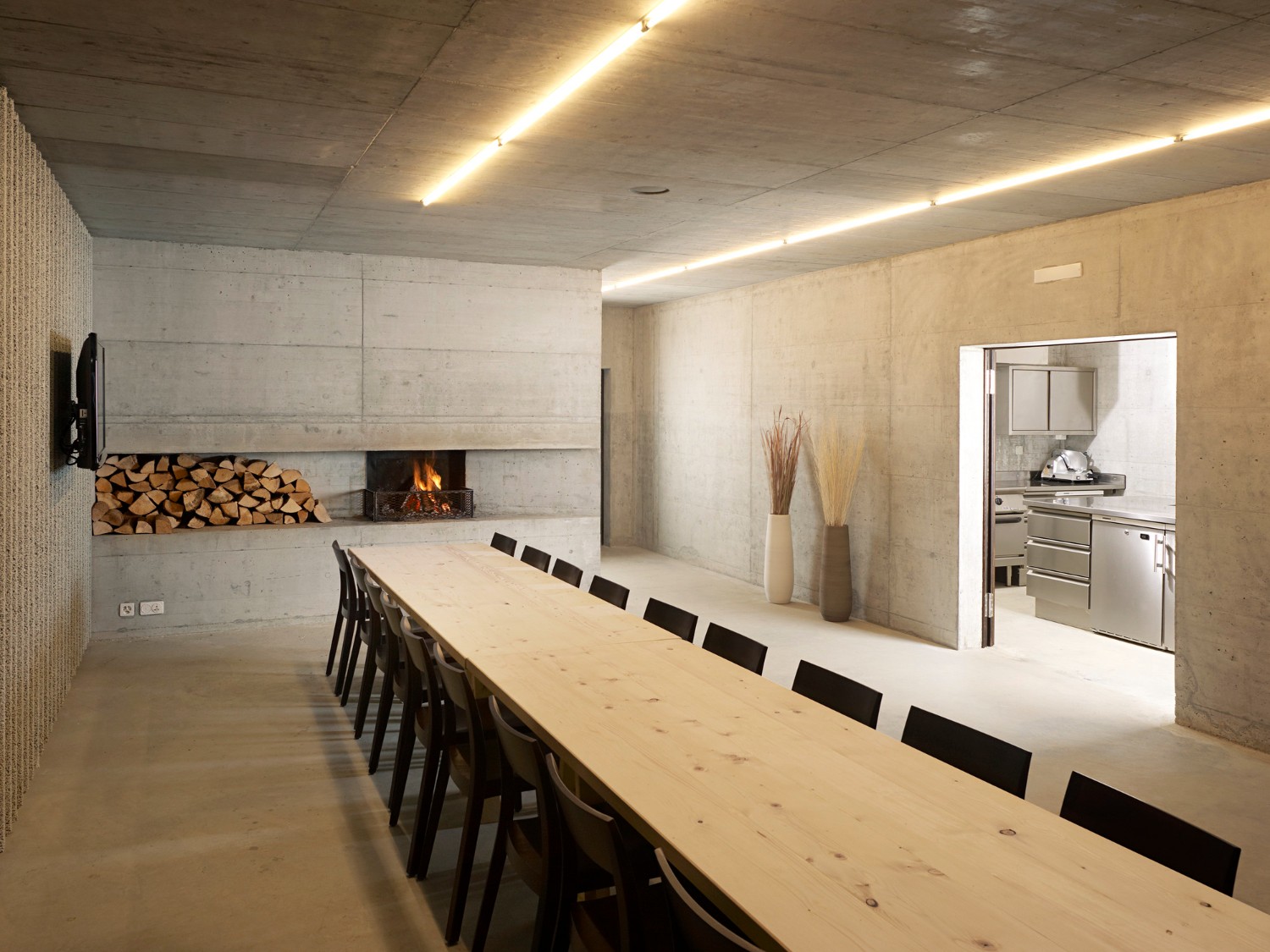 Community Shelter by frundgallina — A dining space carved from raw concrete, its board-formed walls bearing textured impressions of construction shuttering.