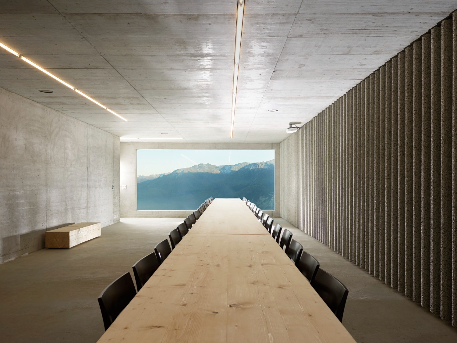 Community Shelter by frundgallina — A linear conference room extends toward a panoramic window framing distant mountains.