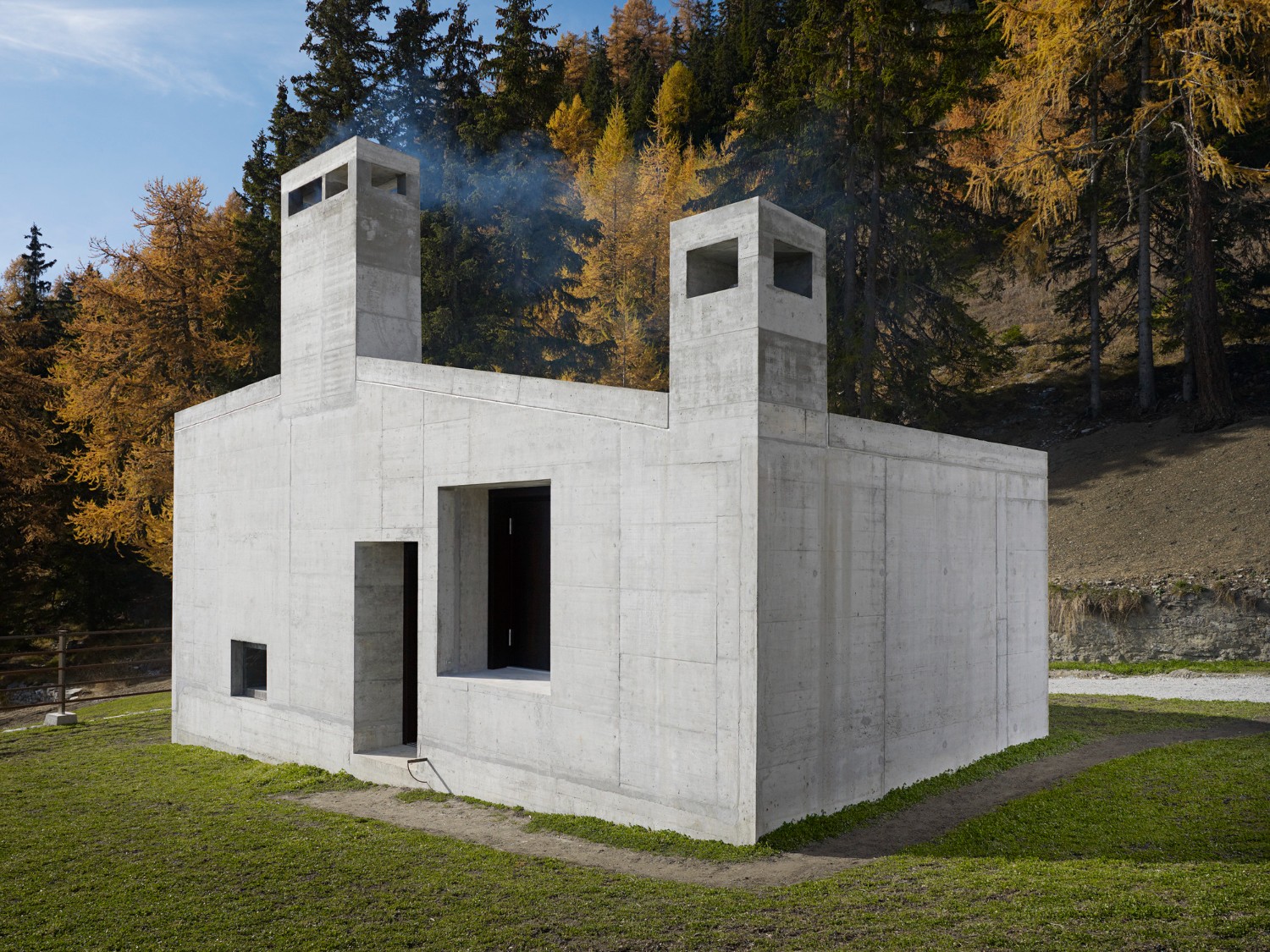 Community Shelter by frundgallina — A monolithic concrete structure positioned on sloped alpine terrain, its massing defined by site topography.