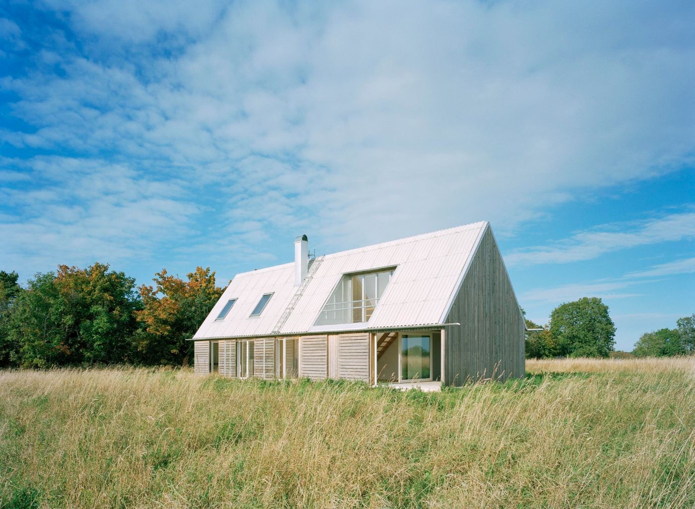 Sommarhus at Stora Gasmora by LLP Arkitektkontor — The gabled timber house stands isolated in an open meadow plateau facing the Baltic Sea.
