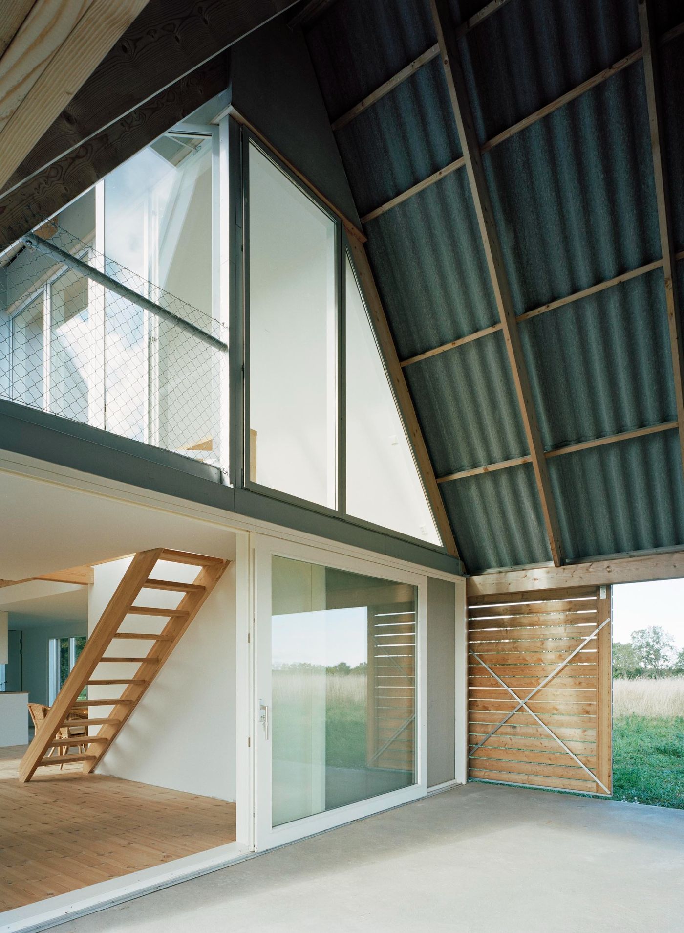 Sommarhus at Stora Gasmora by LLP Arkitektkontor — The entrance volume of Sommarhus at Stora Gasmora unfolds as a double-height space articulated by exposed timber roof trusses and corrugated metal cladding...
