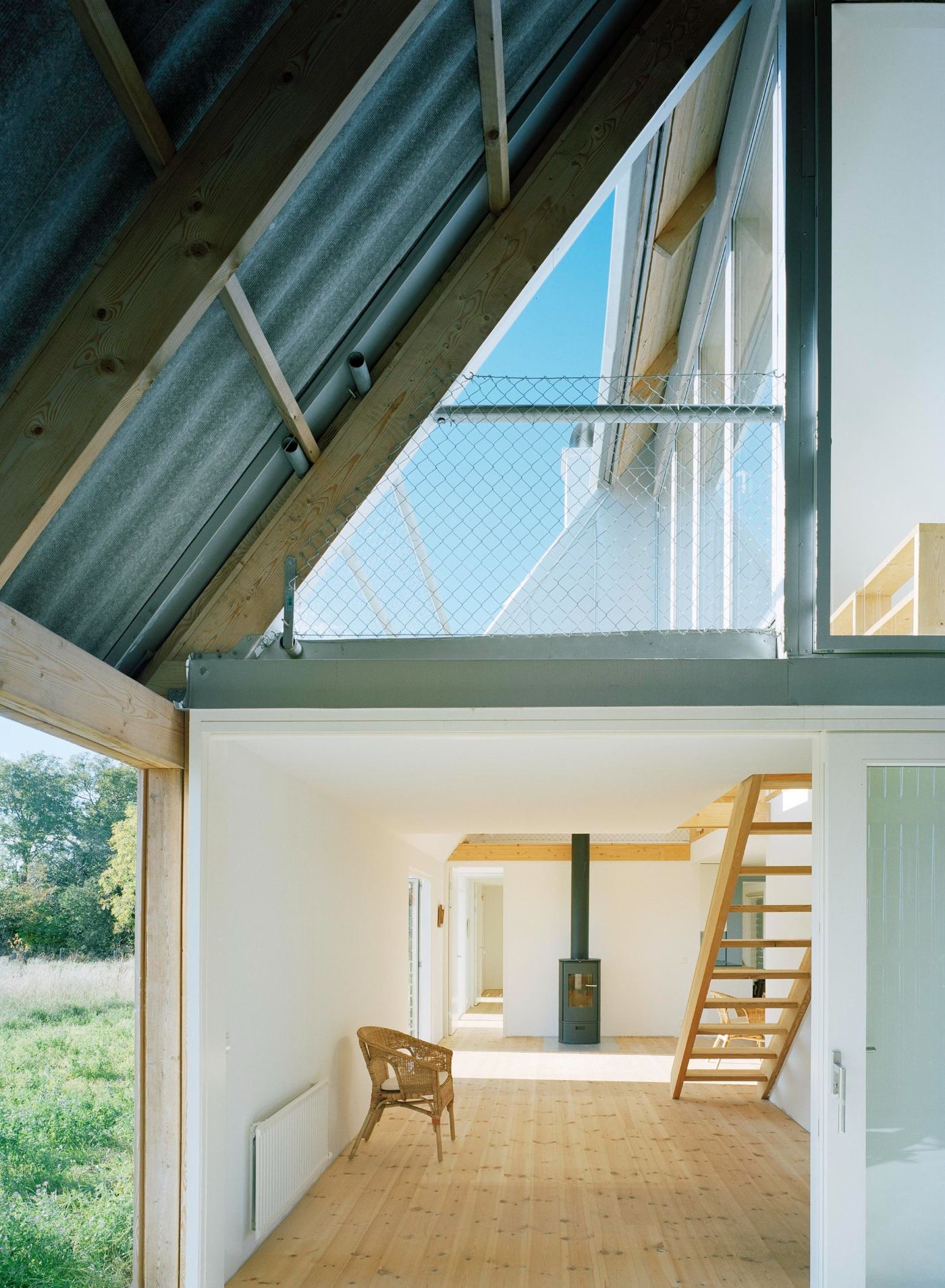 Sommarhus at Stora Gasmora by LLP Arkitektkontor — Interior view of the Sommarhus entrance space, framed by post-and-beam timber structure with exposed roof trusses and corrugated metal cladding overhead.