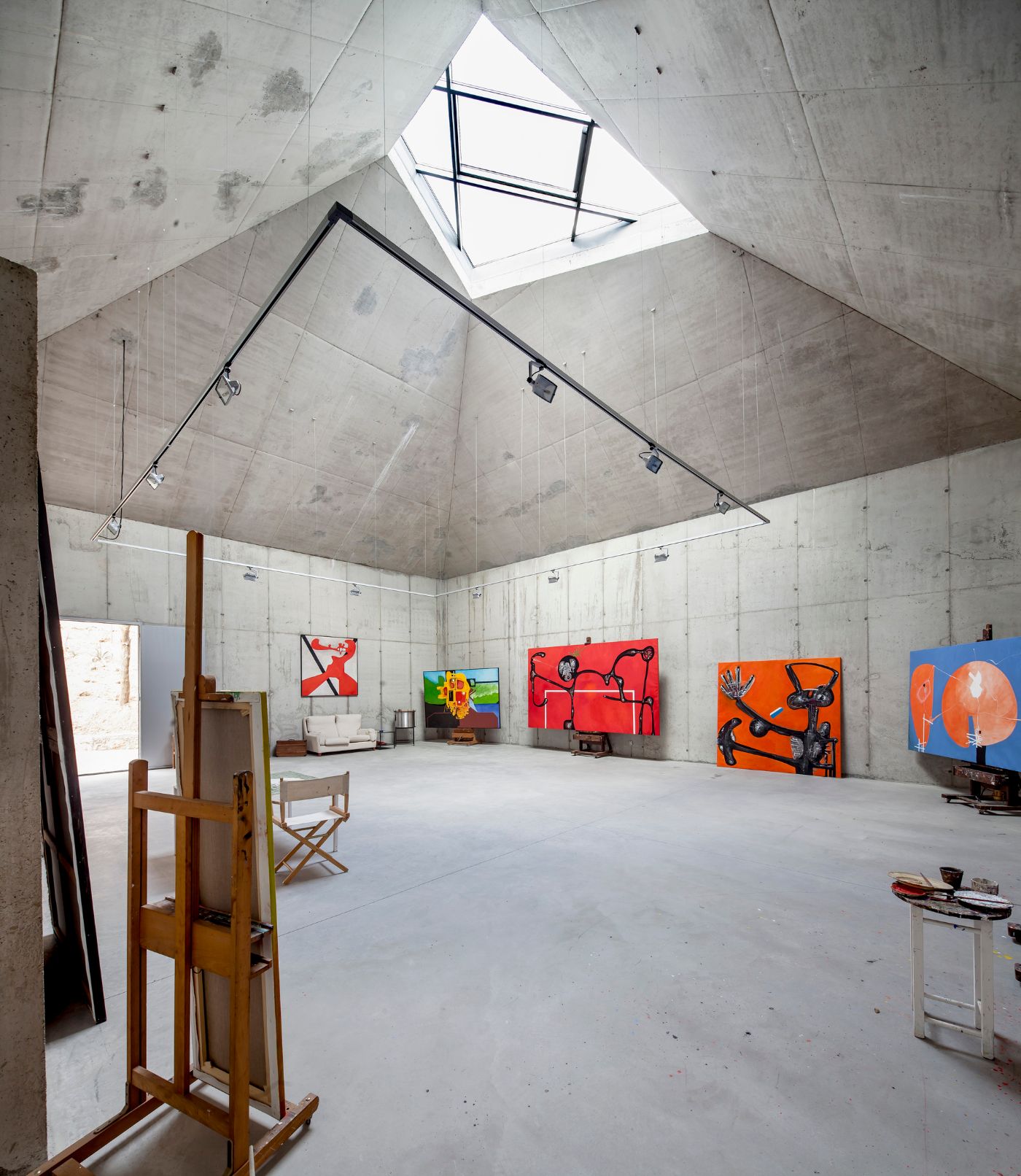 Arranz Bravo Studio by Garcés - De Seta - Bonet Arquitectes — Interior view of the artist studio featuring a pitched concrete ceiling with integrated skylight and steel structural framework.