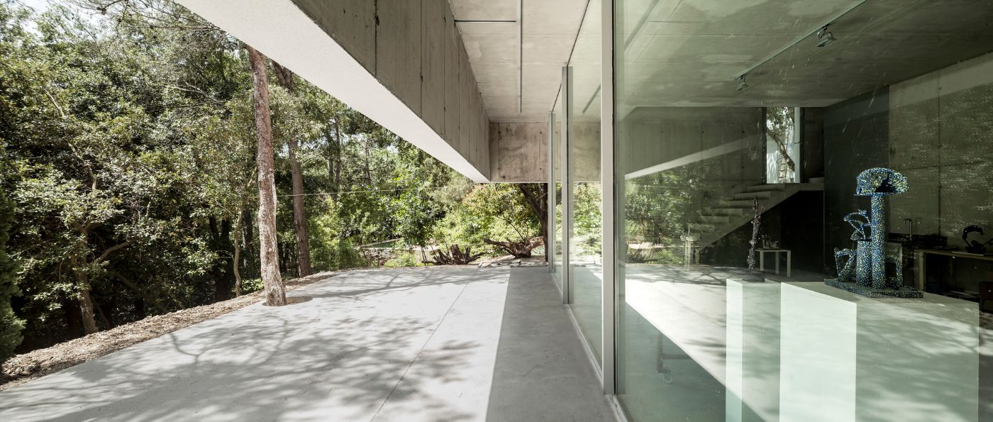 Arranz Bravo Studio by Garcés - De Seta - Bonet Arquitectes — A glazed threshold frames the studio's interior, revealing warmly lit concrete spaces beyond.