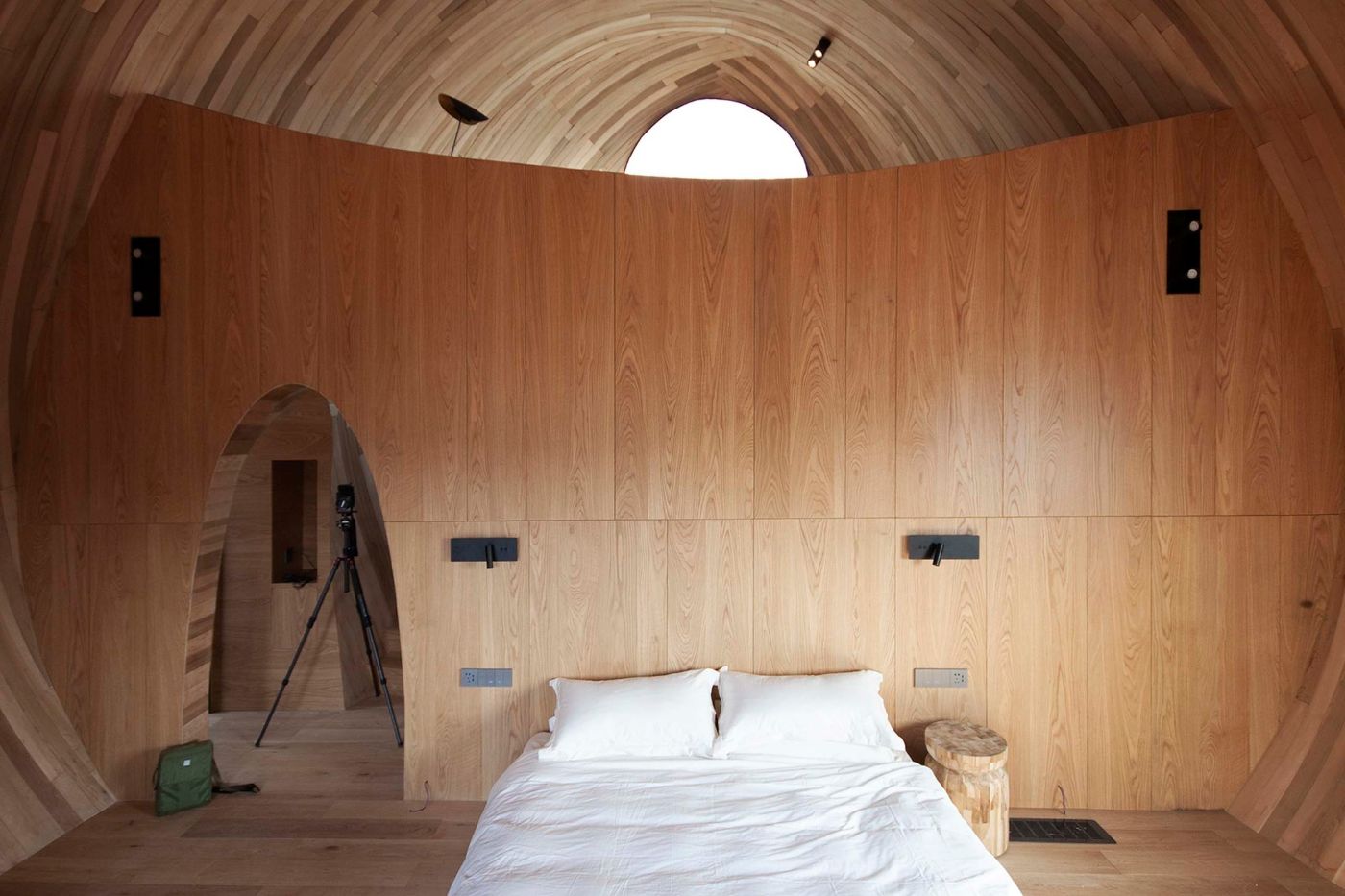 The Seeds Houses by ZJJZ Atelier — Interior of a Seeds House chamber with curved plywood walls meeting a barrel-vault ceiling punctuated by a semicircular skylight.