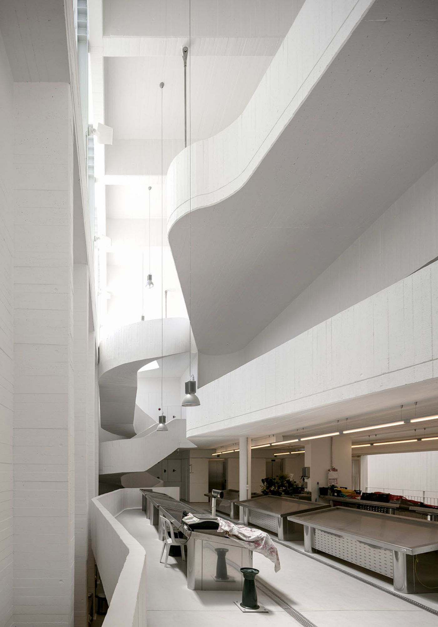 Abrantes Municipal Market by ARX Portugal — The Abrantes Municipal Market's interior reveals a spiraling concrete volume that organizes vertical circulation through the structure's multiple levels.