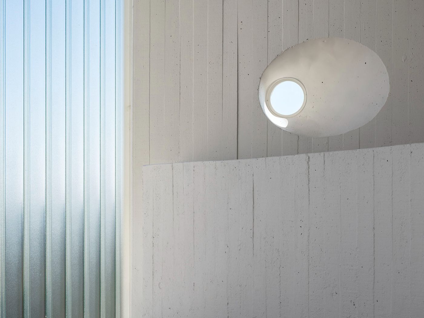 Abrantes Municipal Market by ARX Portugal — A cylindrical concrete light shaft punctures through the market's interior volume, its off-white board-formed surface catching overhead illumination through...