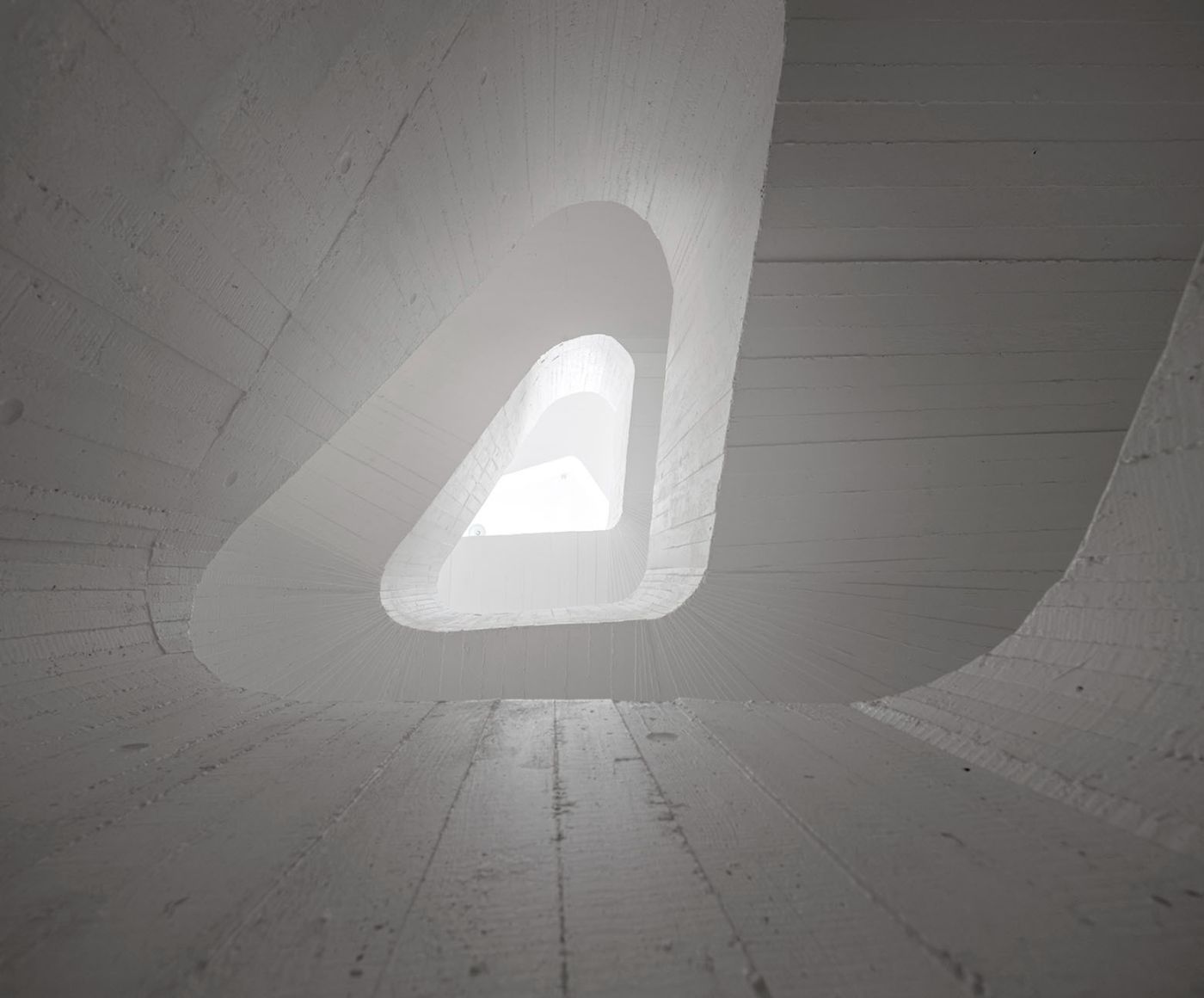 Abrantes Municipal Market by ARX Portugal — Looking upward through a spiraling concrete void, the image captures the Abrantes Municipal Market's dramatic vertical circulation.