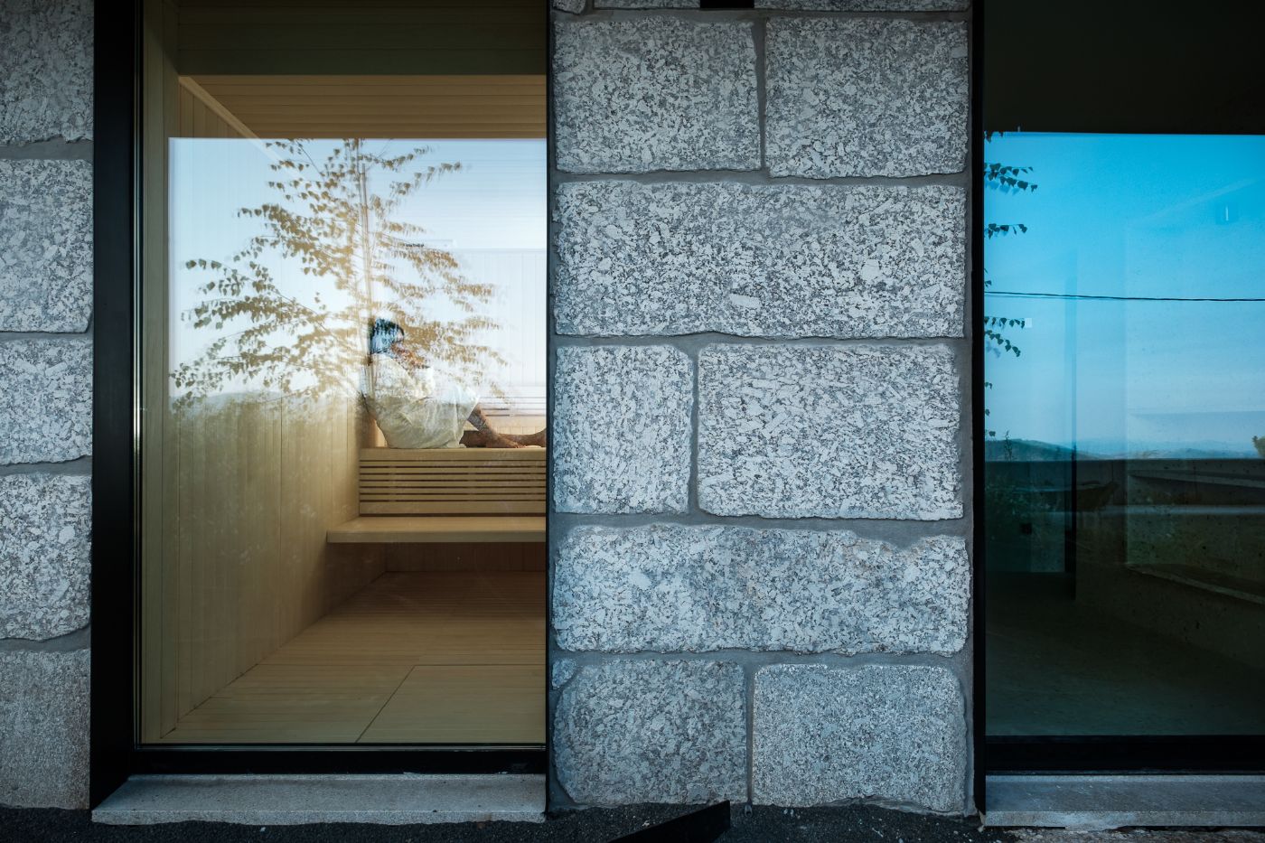 Casa de São Lourenço by P-06 Atelier and Site Specific by P-06, Site Specific, Rogério de Azevedo — A threshold framed by stacked granite masonry with deep mortar joints, the entrance opens onto a timber-floored interior terrace.