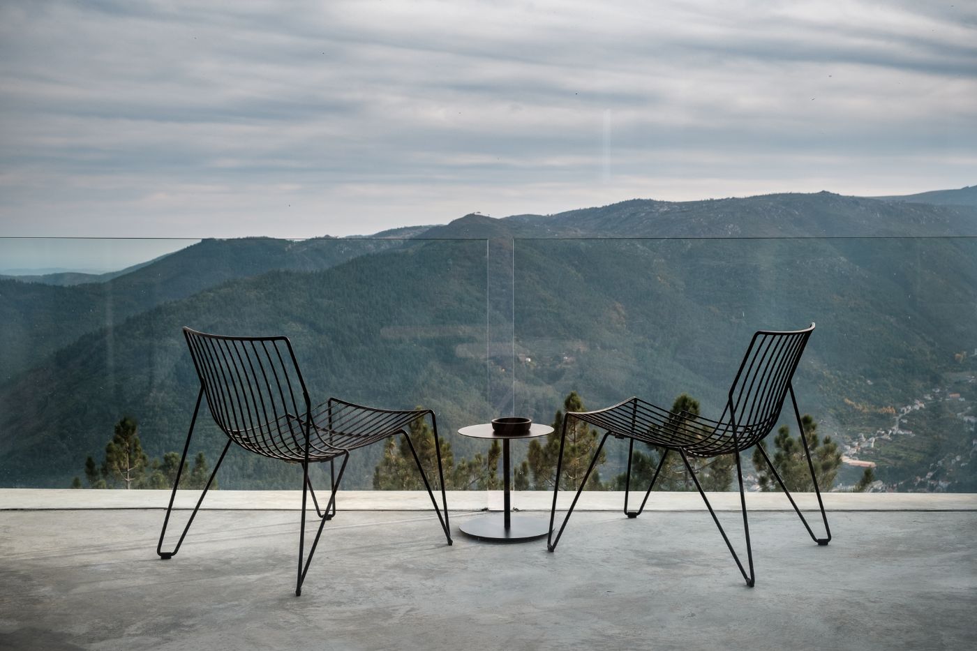 Casa de São Lourenço by P-06 Atelier and Site Specific by P-06, Site Specific, Rogério de Azevedo — Two black metal chairs with continuous linear frames face a small round table across a concrete terrace.