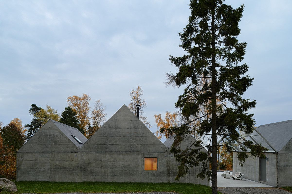 Summerhouse Lagnö by Tham & Videgård Arkitekter — The Summerhouse Lagnö presents its monolithic concrete facade in full southern aspect, revealing the board-formed texture across pitched gable volumes.