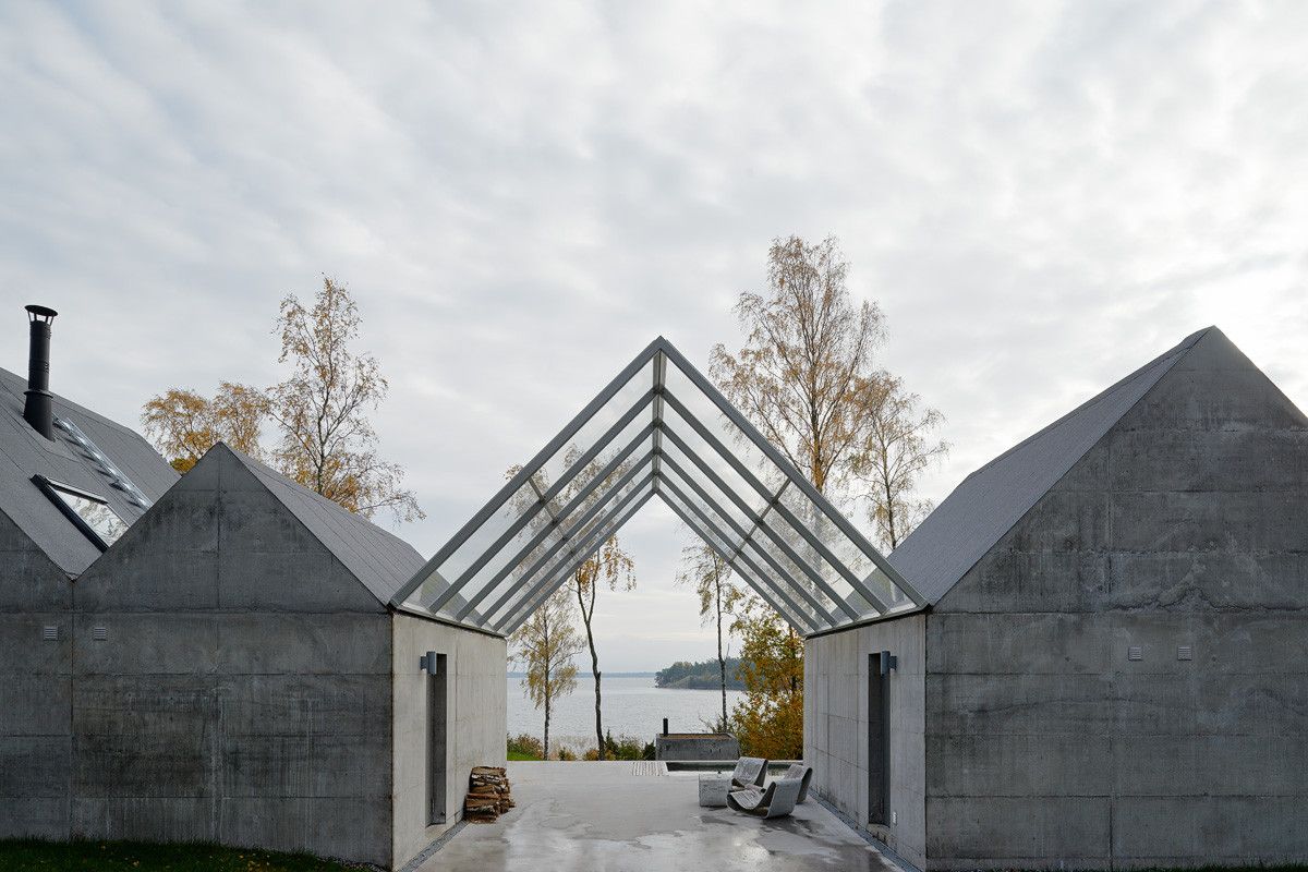 Summerhouse Lagnö by Tham & Videgård Arkitekter — Two monolithic concrete volumes with pitched gable roofs frame a glazed passage opening toward the archipelago.