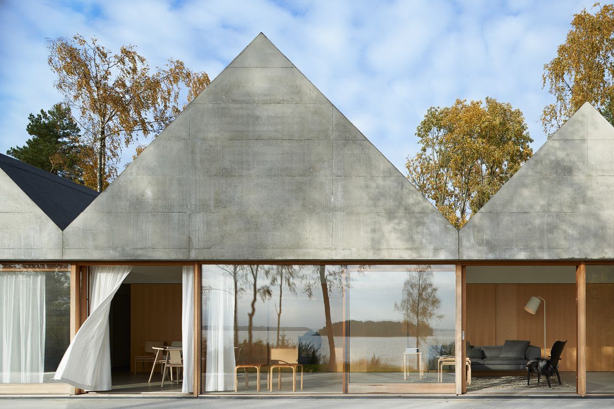 Summerhouse Lagnö by Tham & Videgård Arkitekter — Three concrete volumes with pitched gable roofs dominate the composition, their monolithic forms articulated by horizontal board-mark striations.