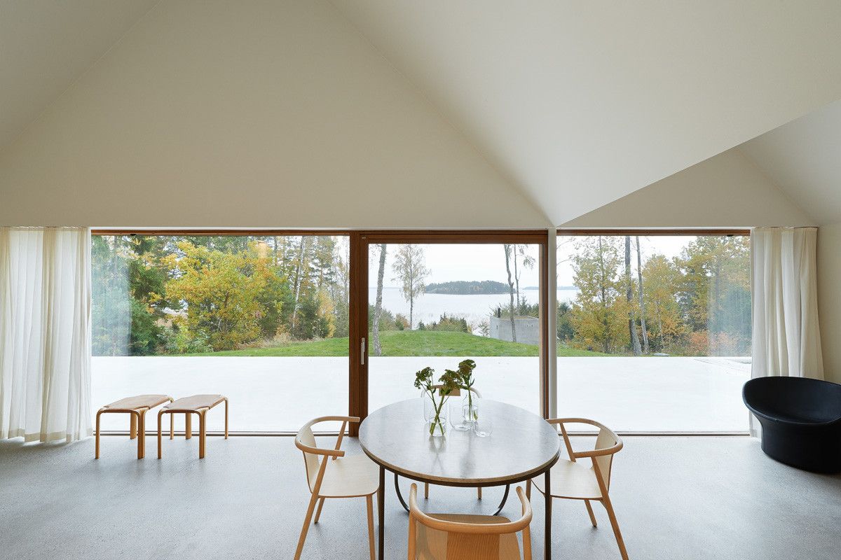 Summerhouse Lagnö by Tham & Videgård Arkitekter — A vaulted interior frames a continuous waterfront prospect through floor-to-ceiling glazing with timber mullions.