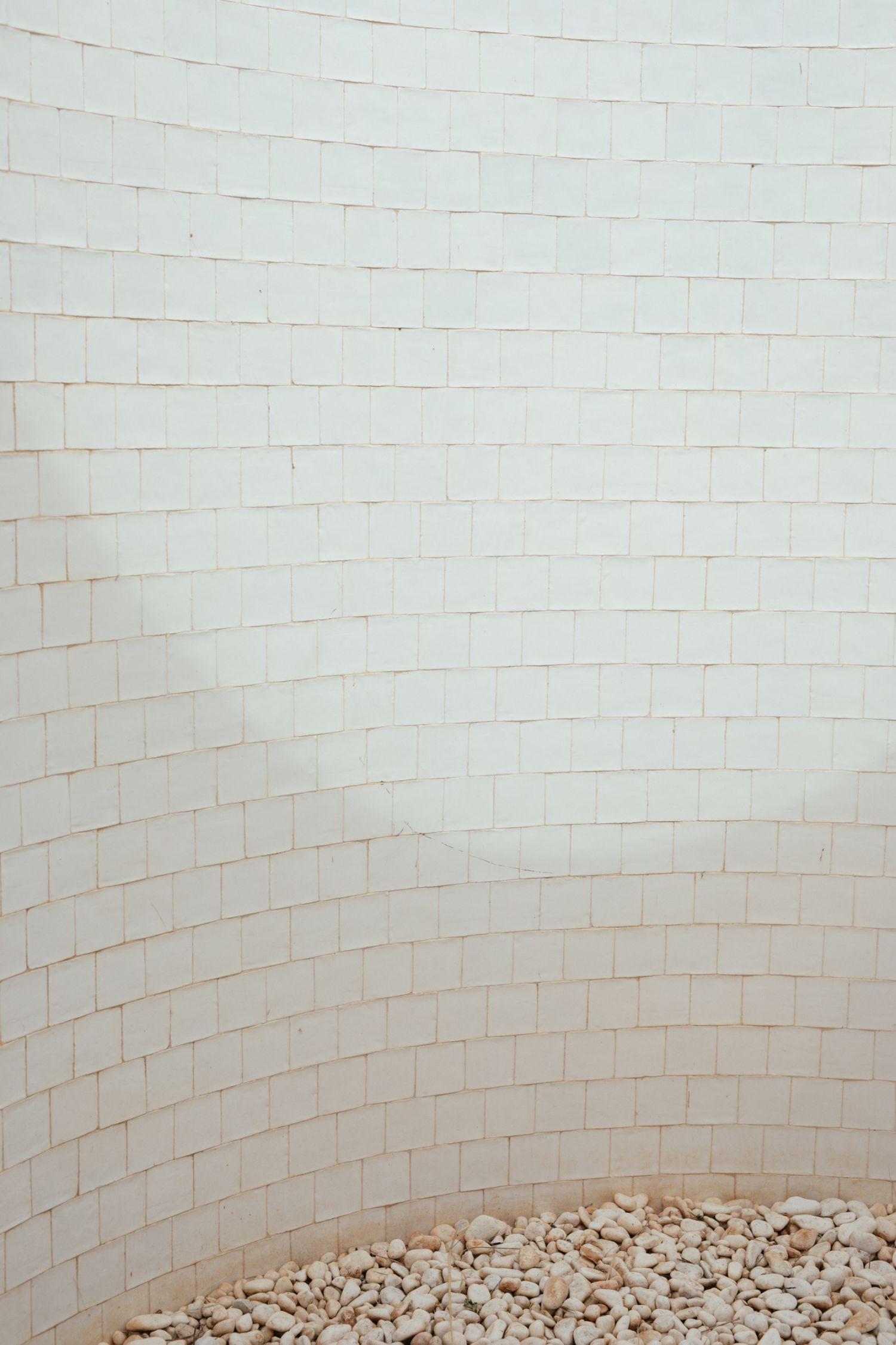Casa na Terra captured by Thisispaper Studio — This close-up detail captures the interior curved surface of Casa na Terra's distinctive roof structure, showcasing the rhythmic pattern of white ceramic...