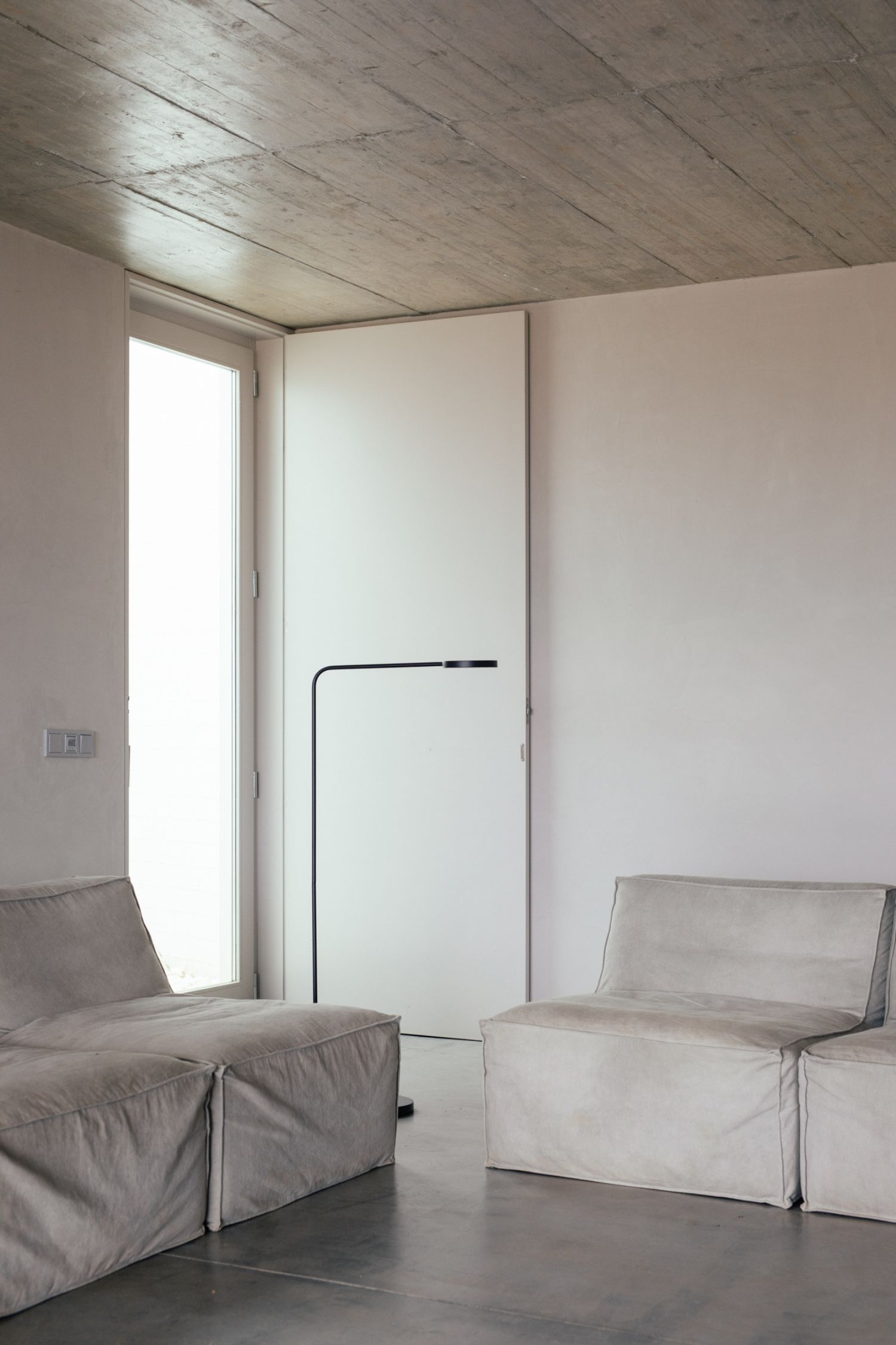 Casa na Terra captured by Thisispaper Studio — Interior passage with white fabric-draped seating elements positioned symmetrically on a dark polished floor.