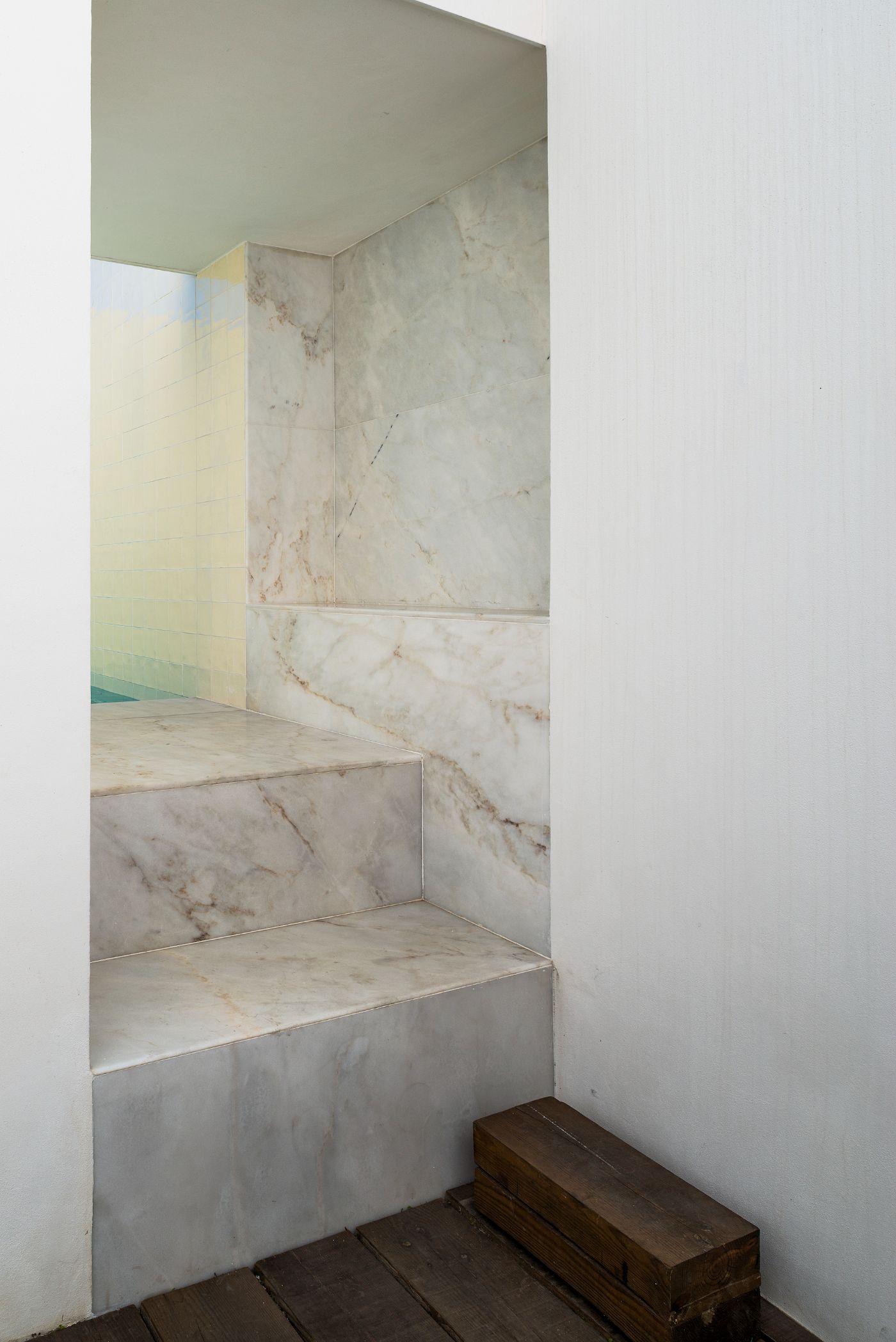 House in Alfama by Matos Gameiro Arquitectos by Pedro Matos Gameiro — A stepped alcove interior clad entirely in veined marble with warm ochre and grey tonal variation.