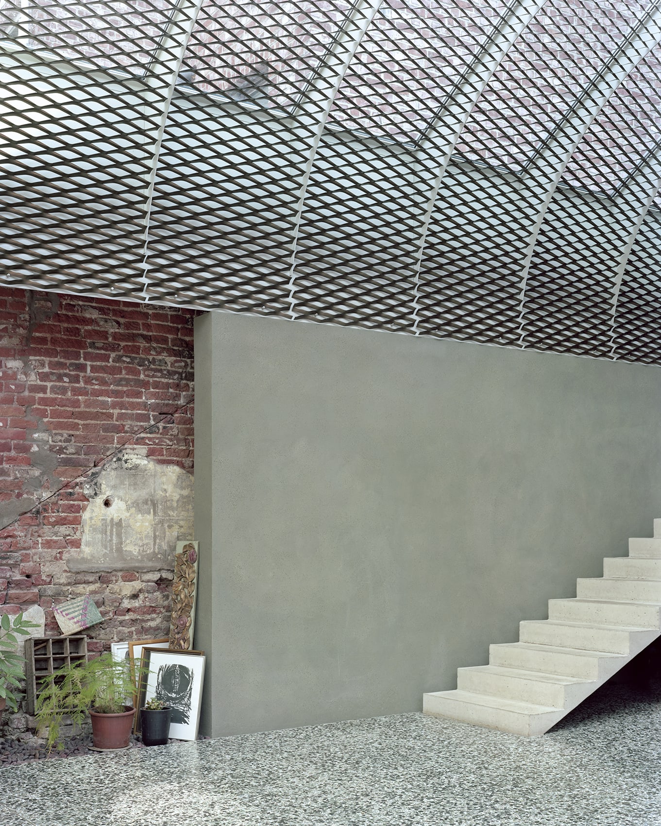 ‘Room in the City’ by 51N4E — A concrete interior volume anchored by a monolithic stair ascending to the right, its cream-coloured treads cantilevered into the space.