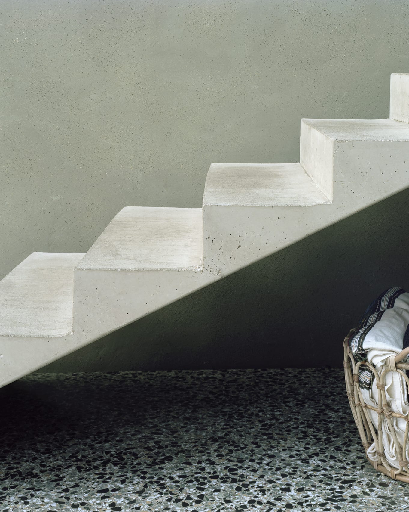 ‘Room in the City’ by 51N4E — A concrete staircase ascends in uniform steps against a rendered wall, its monolithic form casting sharp shadows.