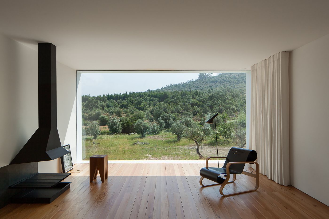 Fonte Boa House by João Mendes Ribeiro — Interior view of Fonte Boa House looking toward the olive grove landscape through a continuous horizontal strip window.