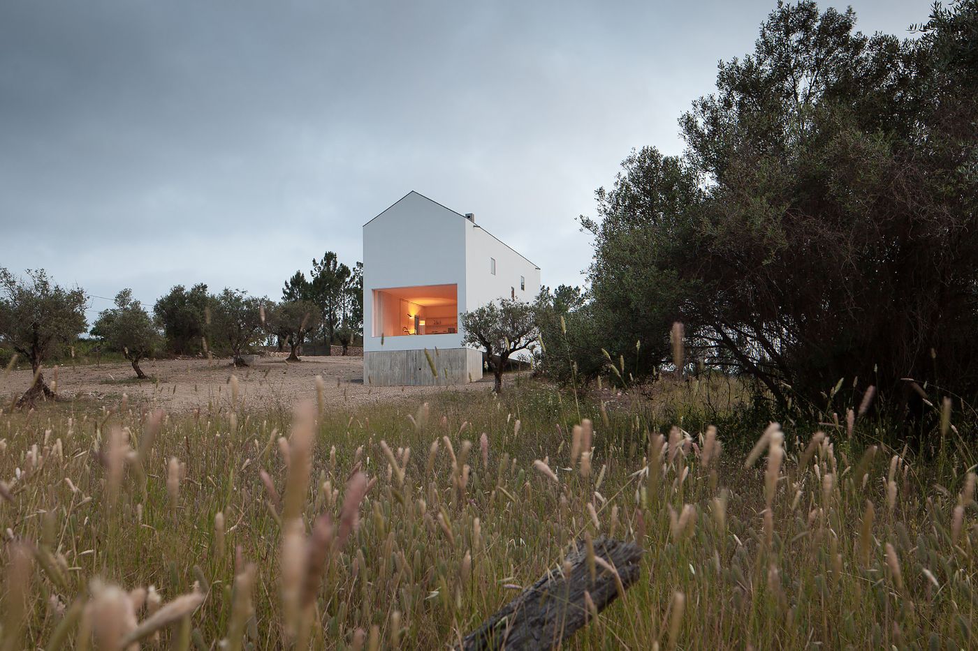 Fonte Boa House by João Mendes Ribeiro — The Fonte Boa House emerges from its rural setting as a two-part composition: a rendered white upper volume housing living spaces sits atop a raw concrete...