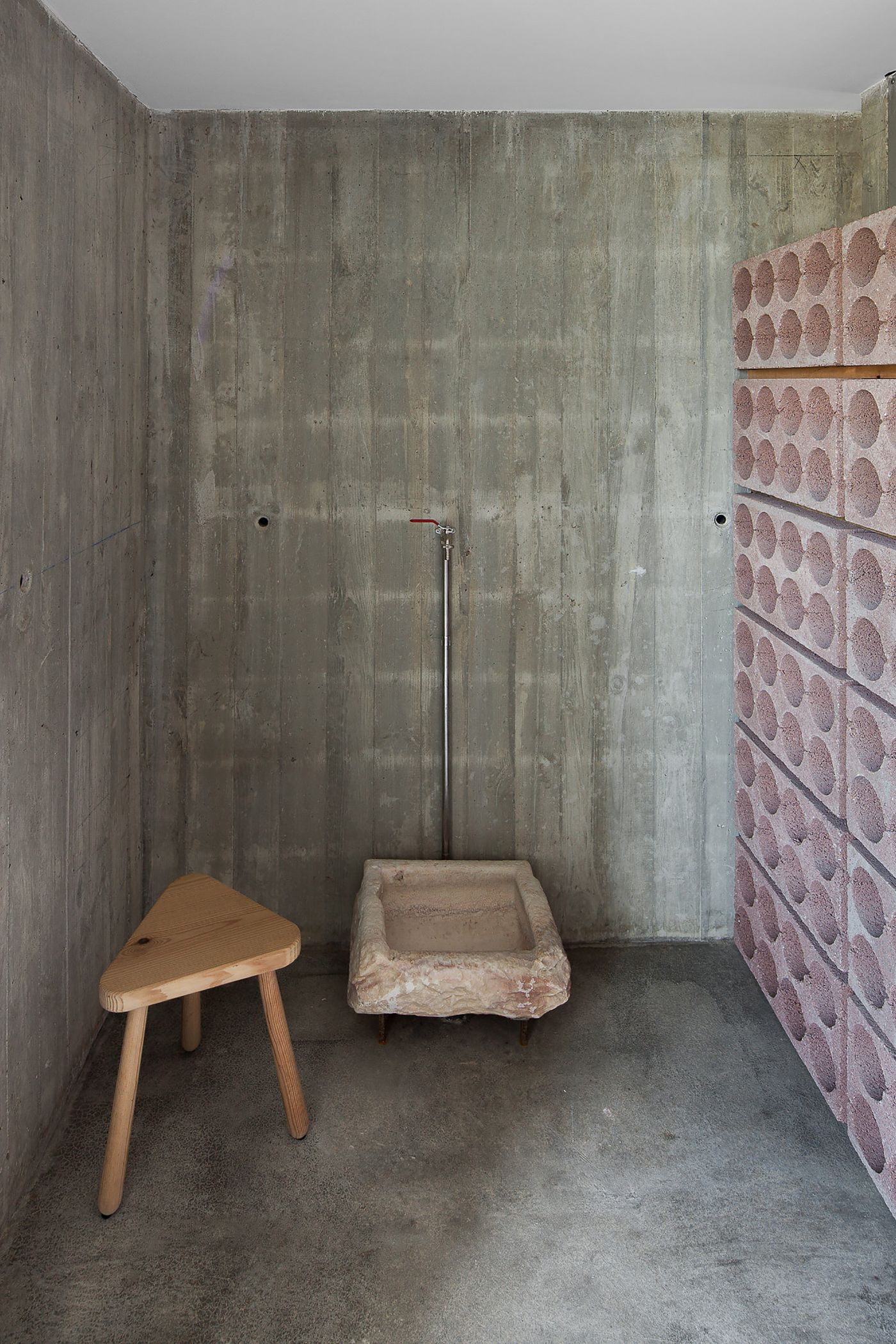 Fonte Boa House by João Mendes Ribeiro — This interior photograph documents a utilitarian space within the Fonte Boa House, showing the raw concrete construction beneath the building's rendered...