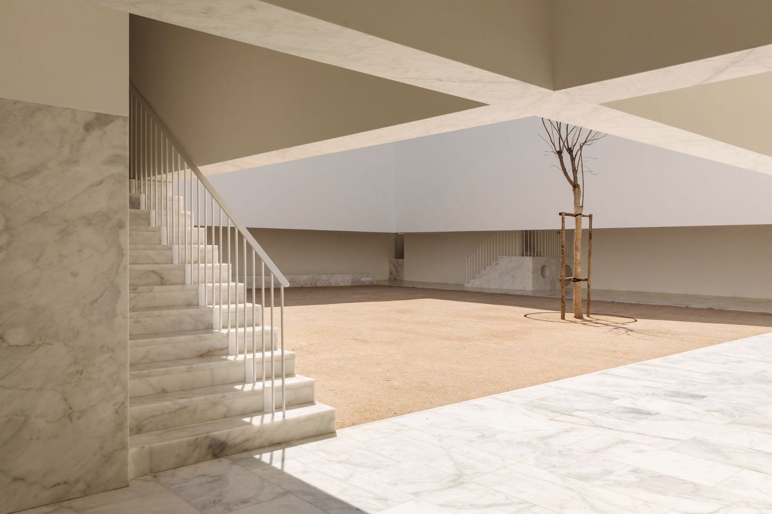 Grândola’s Library and Municipal Archive by Matos Gameiro Arquitectos + Pedro Domingos Arquitectos — A rendered white interior volume opens onto a sandy plaza through a continuous threshold.