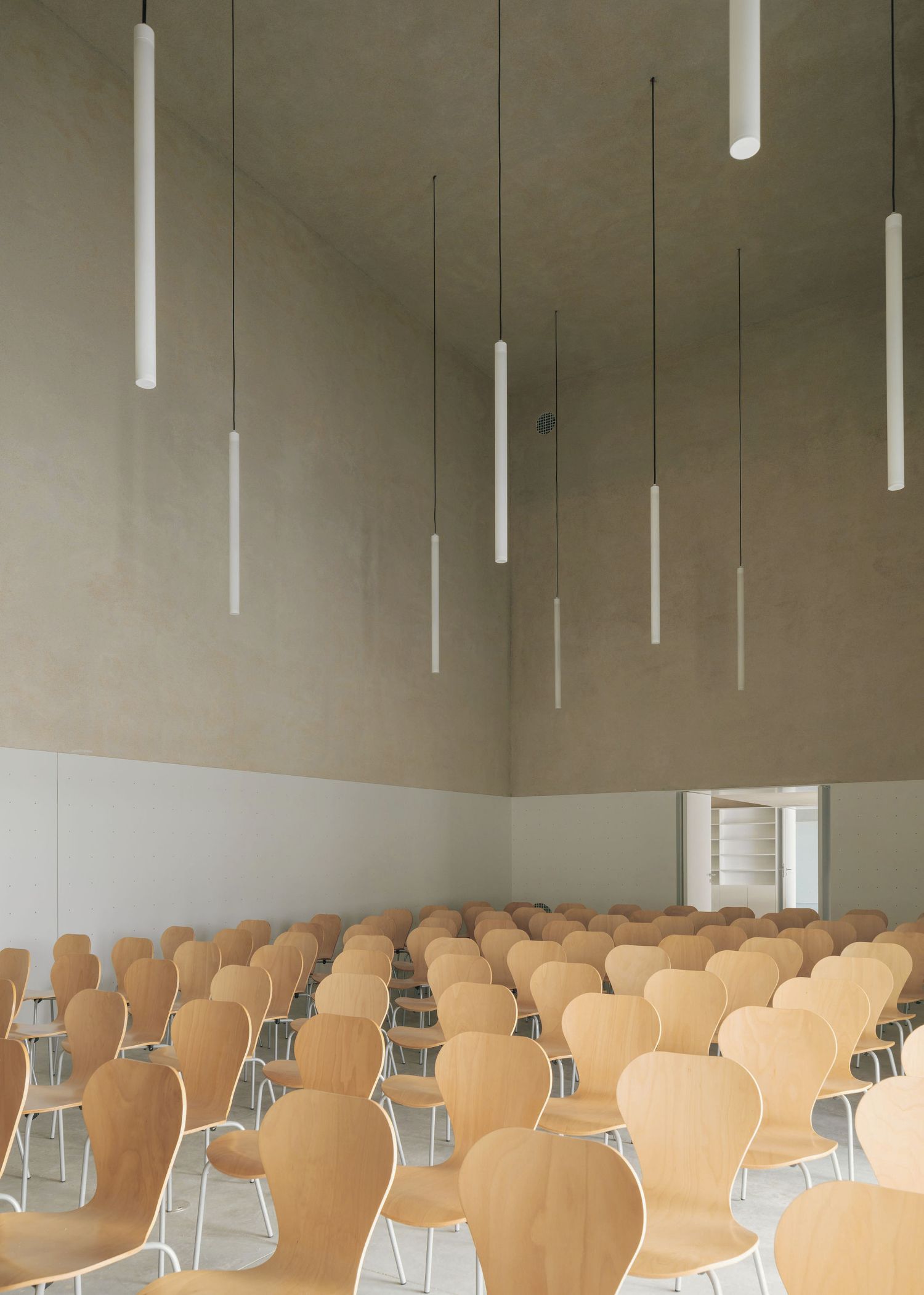 Grândola’s Library and Municipal Archive by Matos Gameiro Arquitectos + Pedro Domingos Arquitectos — A municipal assembly hall demonstrating modular spatial design through repetitive wooden chairs arranged in uniform rows.