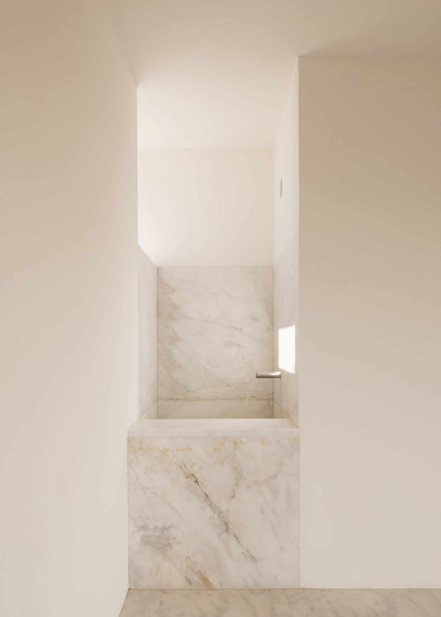 Grândola’s Library and Municipal Archive by Matos Gameiro Arquitectos + Pedro Domingos Arquitectos — A marble-clad interior volume captured from ground level, revealing the architectural language of the Municipal Archive's public threshold.