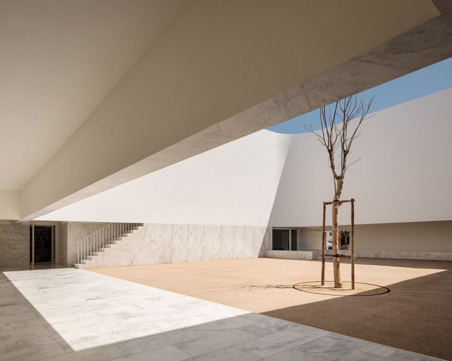 Grândola’s Library and Municipal Archive by Matos Gameiro Arquitectos + Pedro Domingos Arquitectos — A monumental interior courtyard defined by rendered white walls and concrete structural elements.