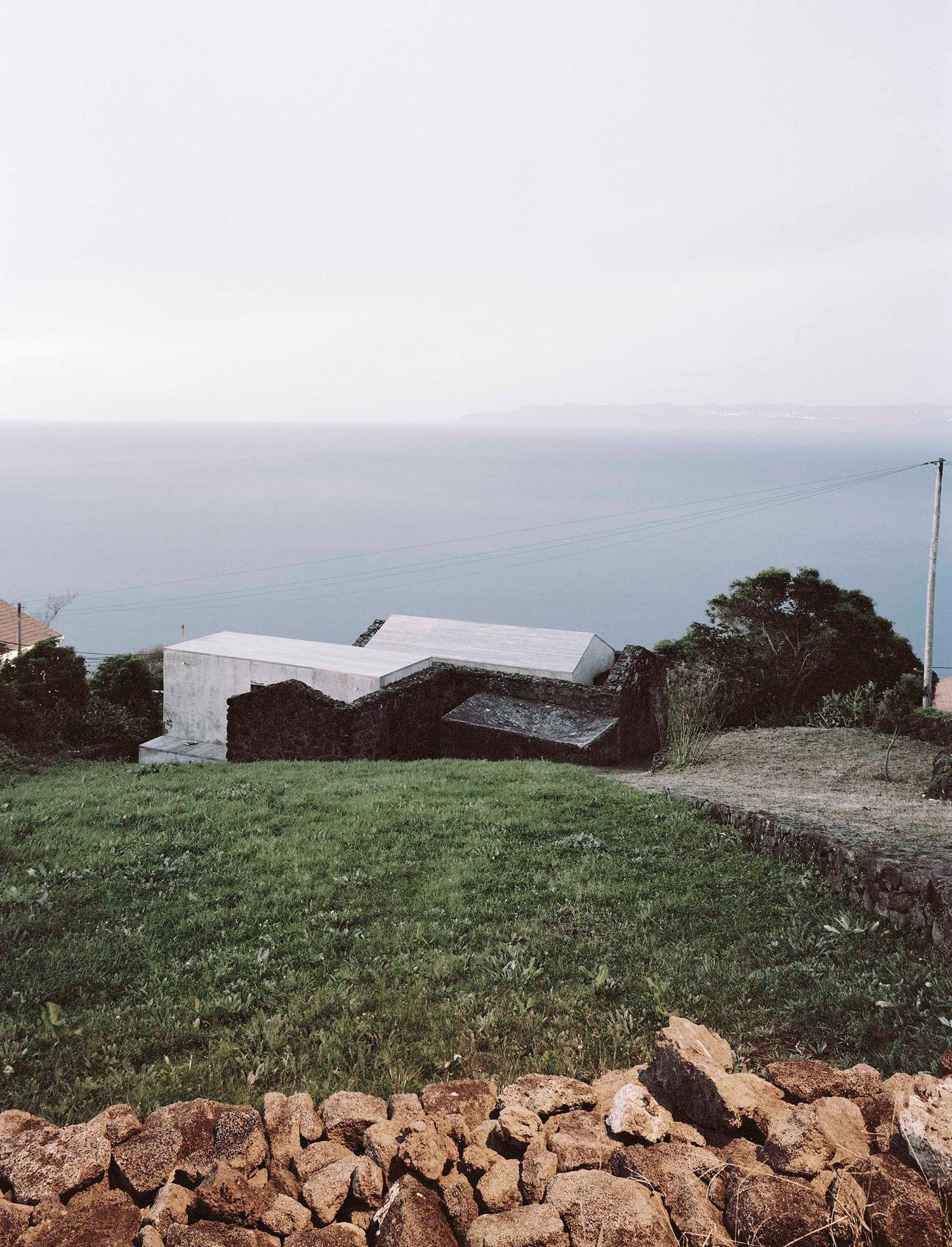 E/C House by SAMI-arquitectos — The E/C House emerges from the volcanic landscape of Pico as a two-part composition.