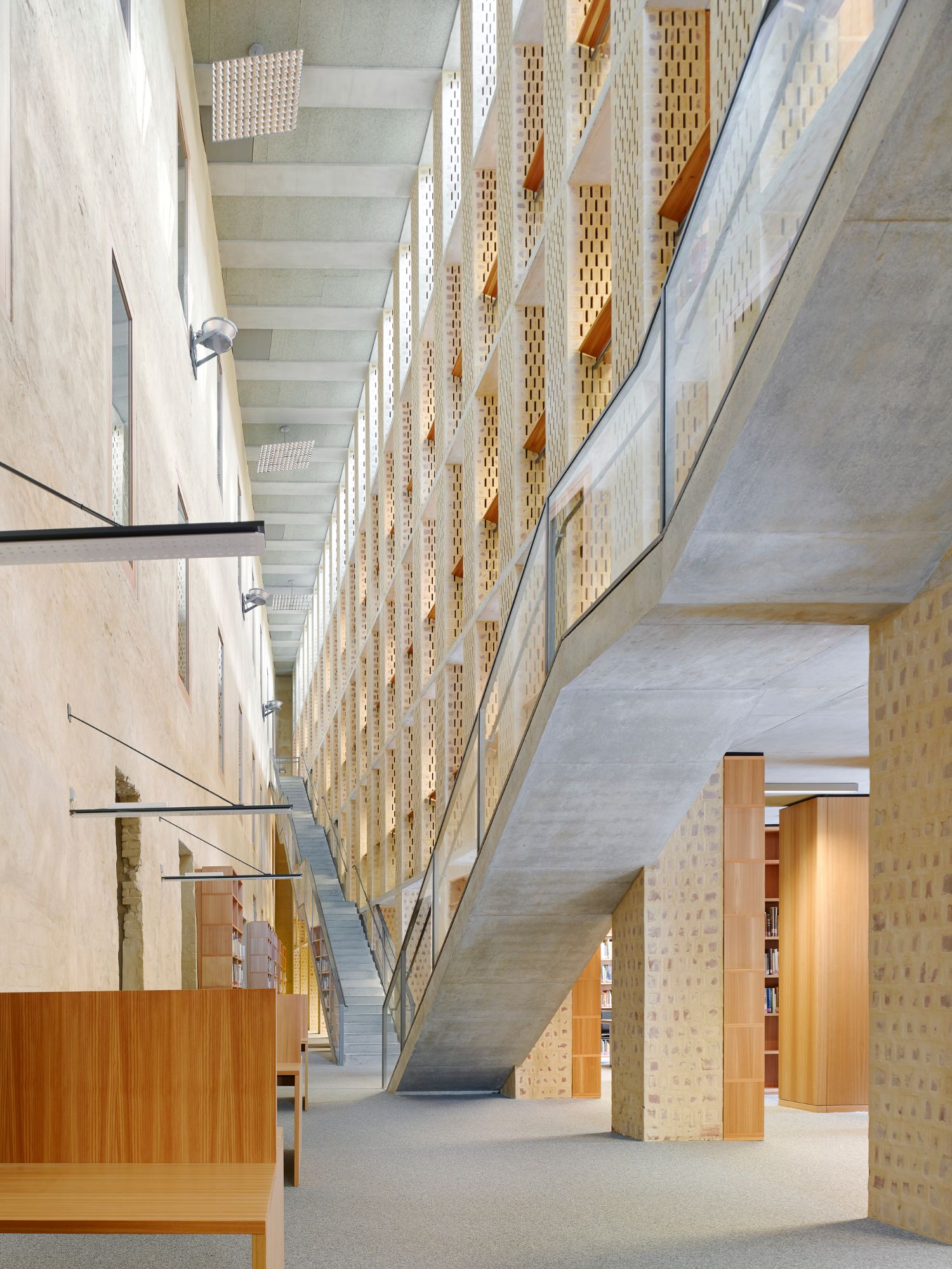 Philosophical Seminar at the Cathedral Square by Peter Böhm Architekten — The atrium corridor extends in linear perspective, defined by concrete soffit beams and perforated brick walls in alternating rhythm.